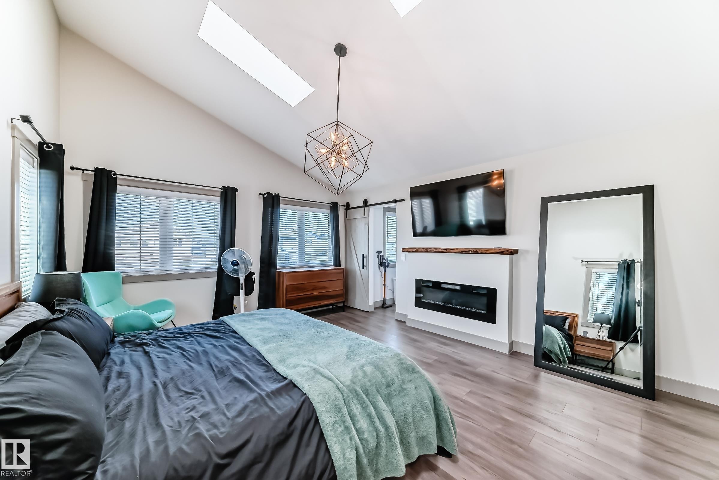 Vaulted ceiling room featuring skylights, wood-finish flooring, and multiple windows - 5263 47 Ave, Calmar, AB - Indoor Photo Showing Bedroom With Fireplace