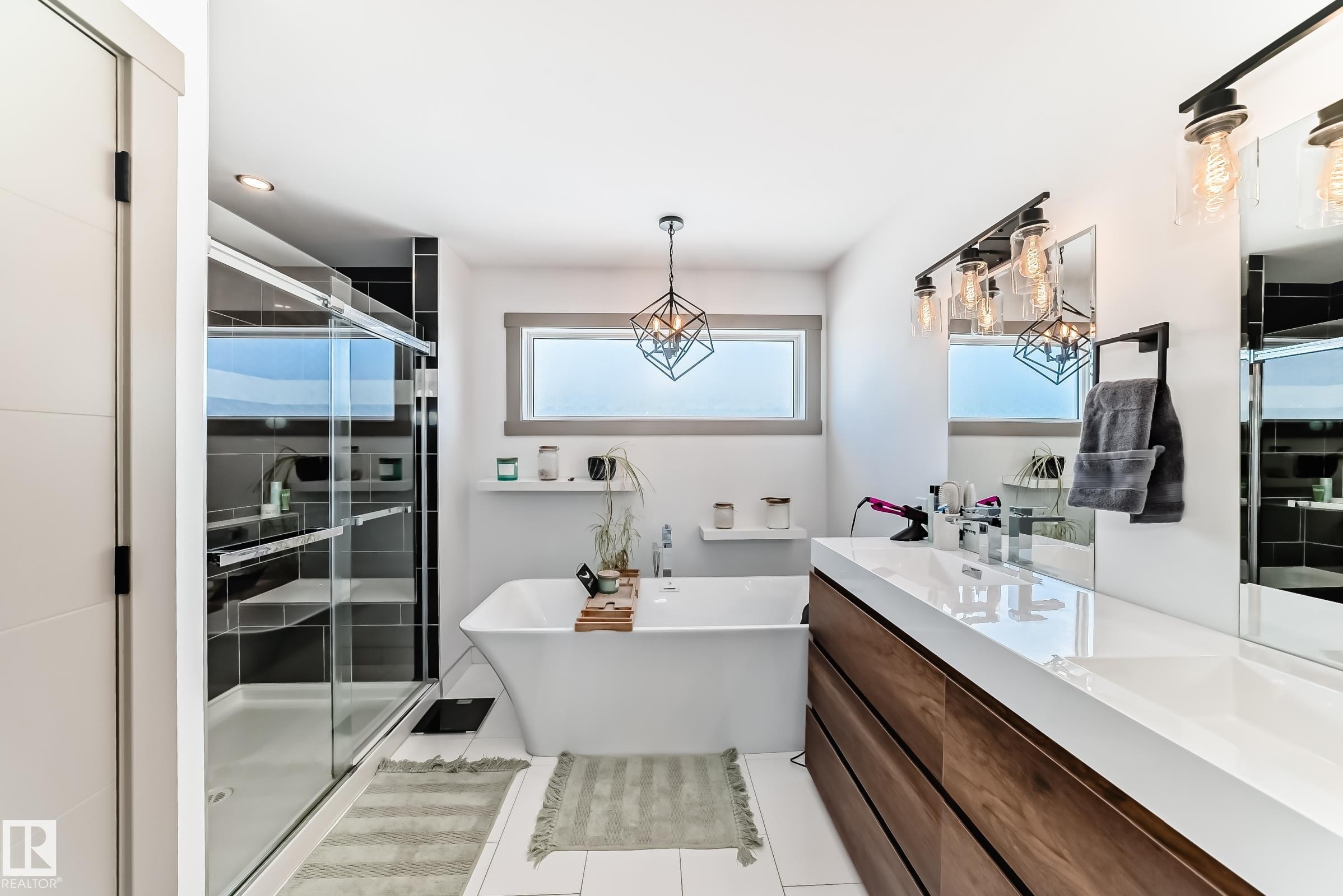 Modern bathroom featuring a freestanding soaking tub, a spacious glass-enclosed shower with dark tile surround, and a long wood-finish vanity with a white countertop - 5263 47 Ave, Calmar, AB - Indoor Photo Showing Bathroom