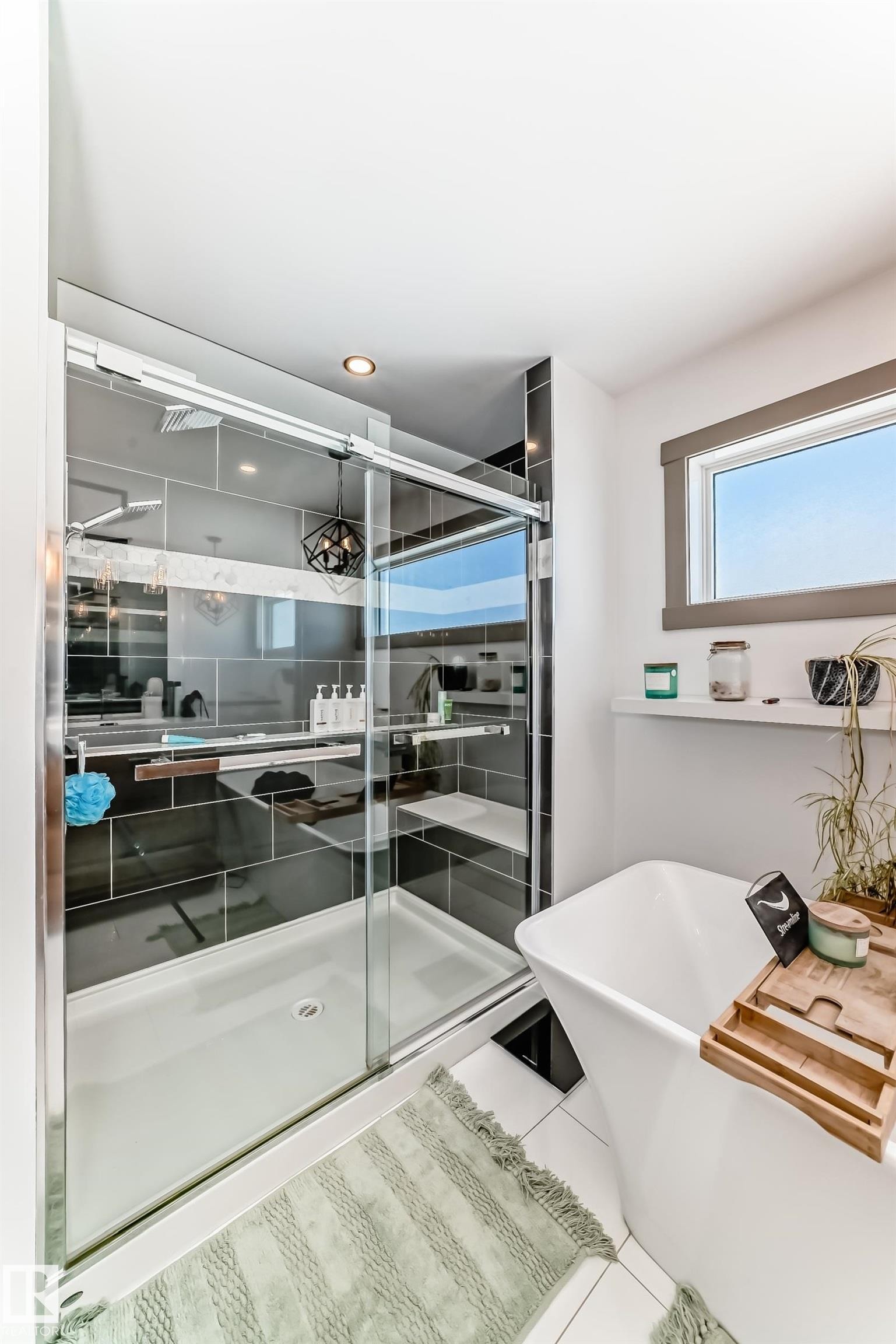 Glass-enclosed shower with dark tile surround and built-in shelving - 5263 47 Ave, Calmar, AB - Indoor