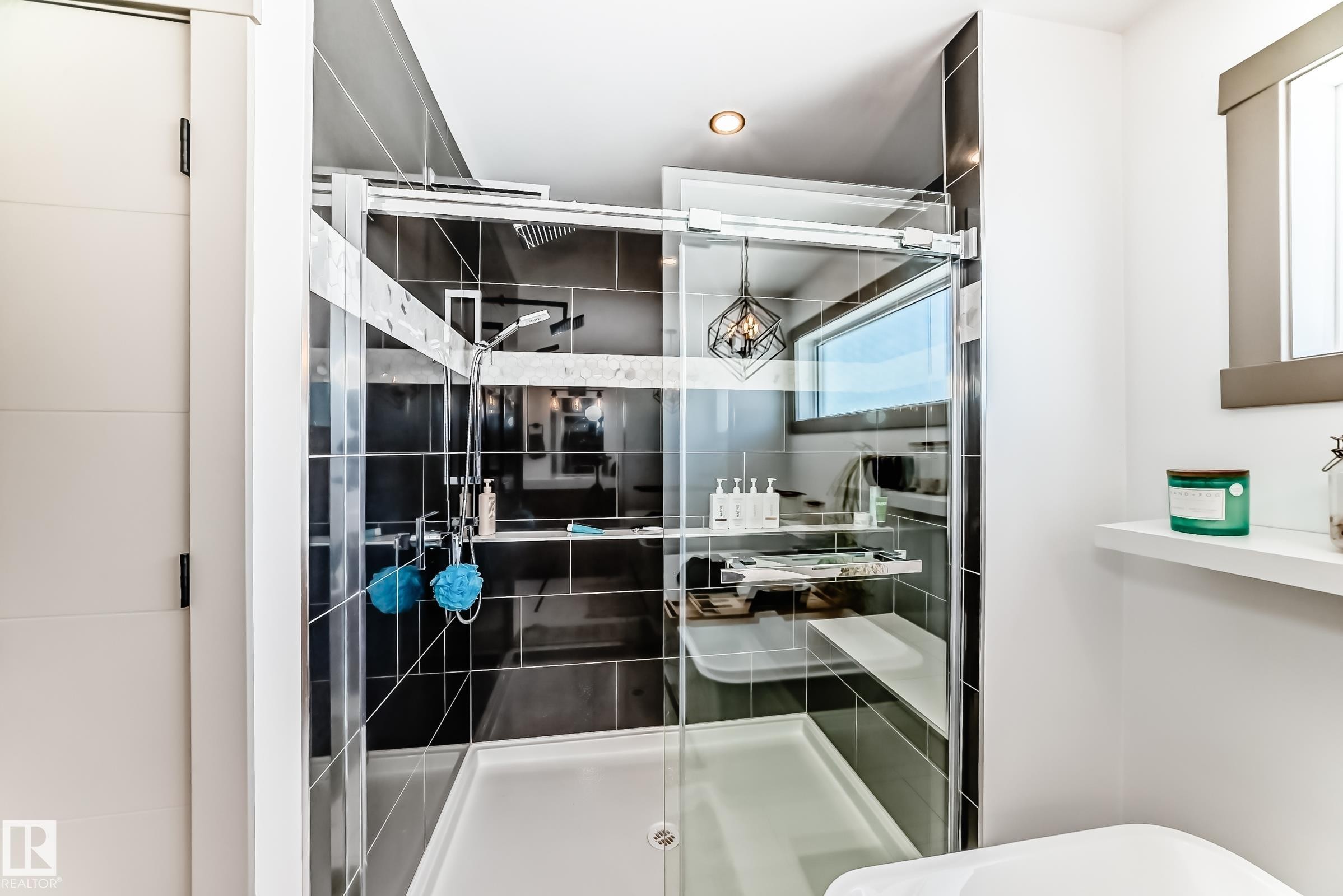 Frameless glass shower enclosure with dark gray subway tile walls and a built-in shower bench - 5263 47 Ave, Calmar, AB - Indoor