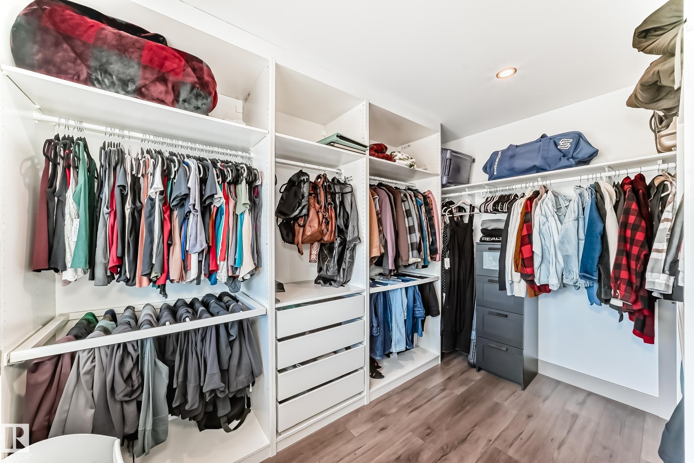 Custom closet system featuring multiple hanging rods, integrated shelving, and built-in drawer storage - 5263 47 Ave, Calmar, AB - Indoor With Storage