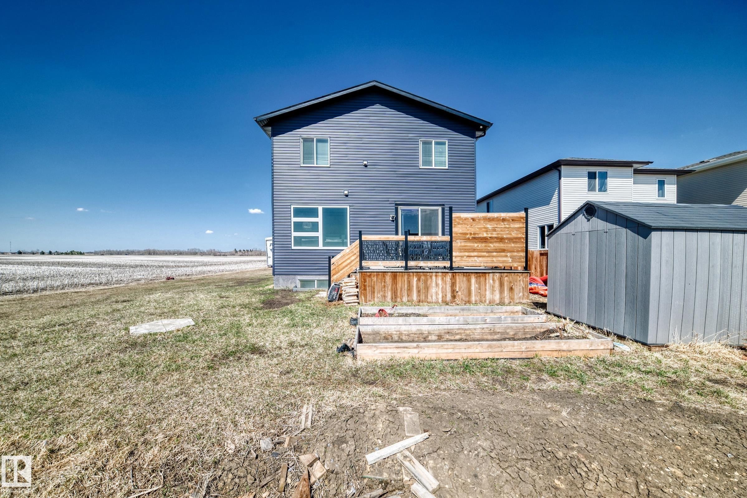 Two-story siding exterior with a multi-level wood deck featuring a black metal railing - 5263 47 Ave, Calmar, AB - Outdoor With Deck Patio Veranda