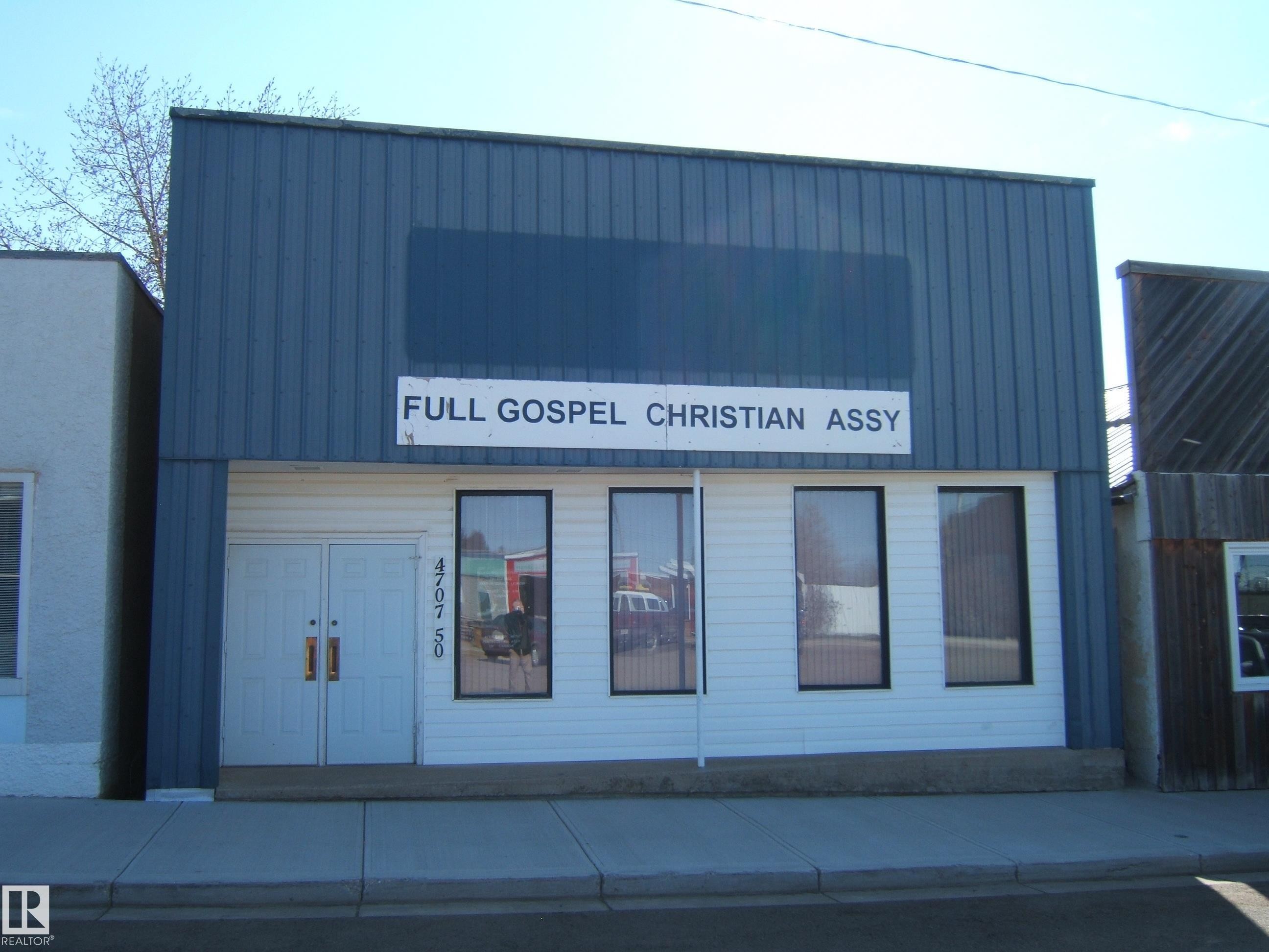 Commercial building featuring a blue metal upper facade and white horizontal siding on the lower level - 4707 50 Street, Two Hills, AB - Outdoor