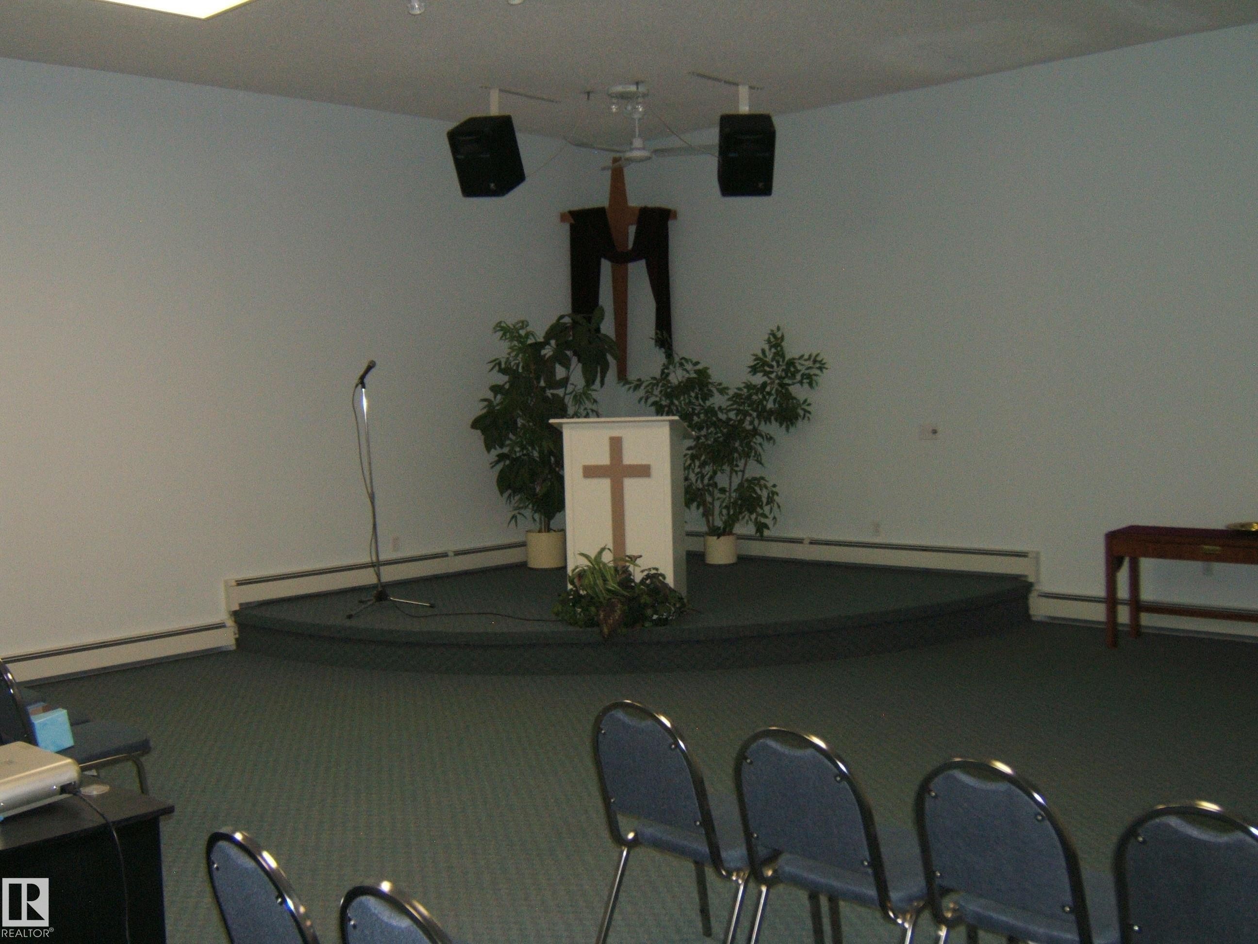 Carpeted platform stage with a central white podium - 4707 50 Street, Two Hills, AB - Indoor Photo Showing Other Room