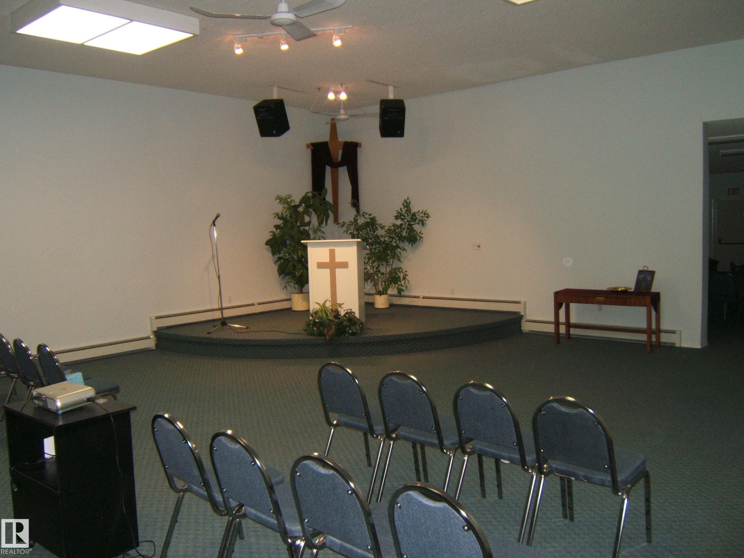 Carpeted room featuring a raised platform with a podium - 4707 50 Street, Two Hills, AB - Indoor