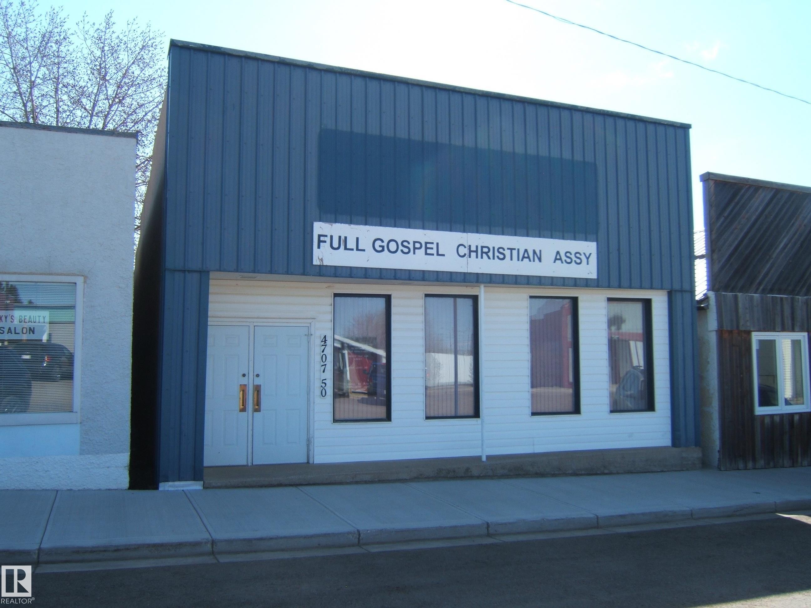 Commercial storefront building featuring a blue corrugated metal upper facade and white horizontal siding on the lower level - 4707 50 Street, Two Hills, AB - Outdoor