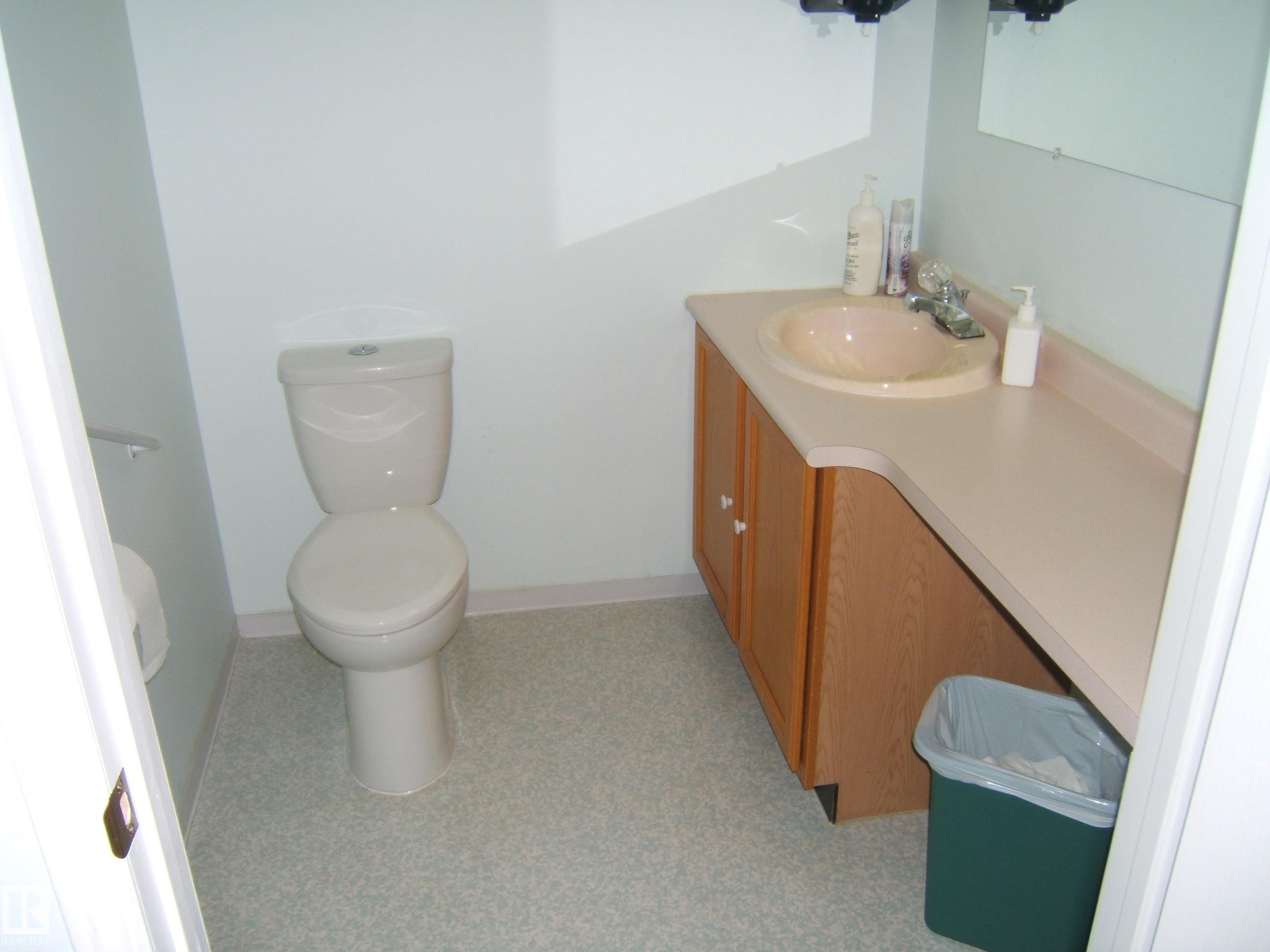 Bathroom featuring a vanity with an integrated sink, laminate countertop, and wood-finish cabinetry - 4707 50 Street, Two Hills, AB - Indoor Photo Showing Bathroom