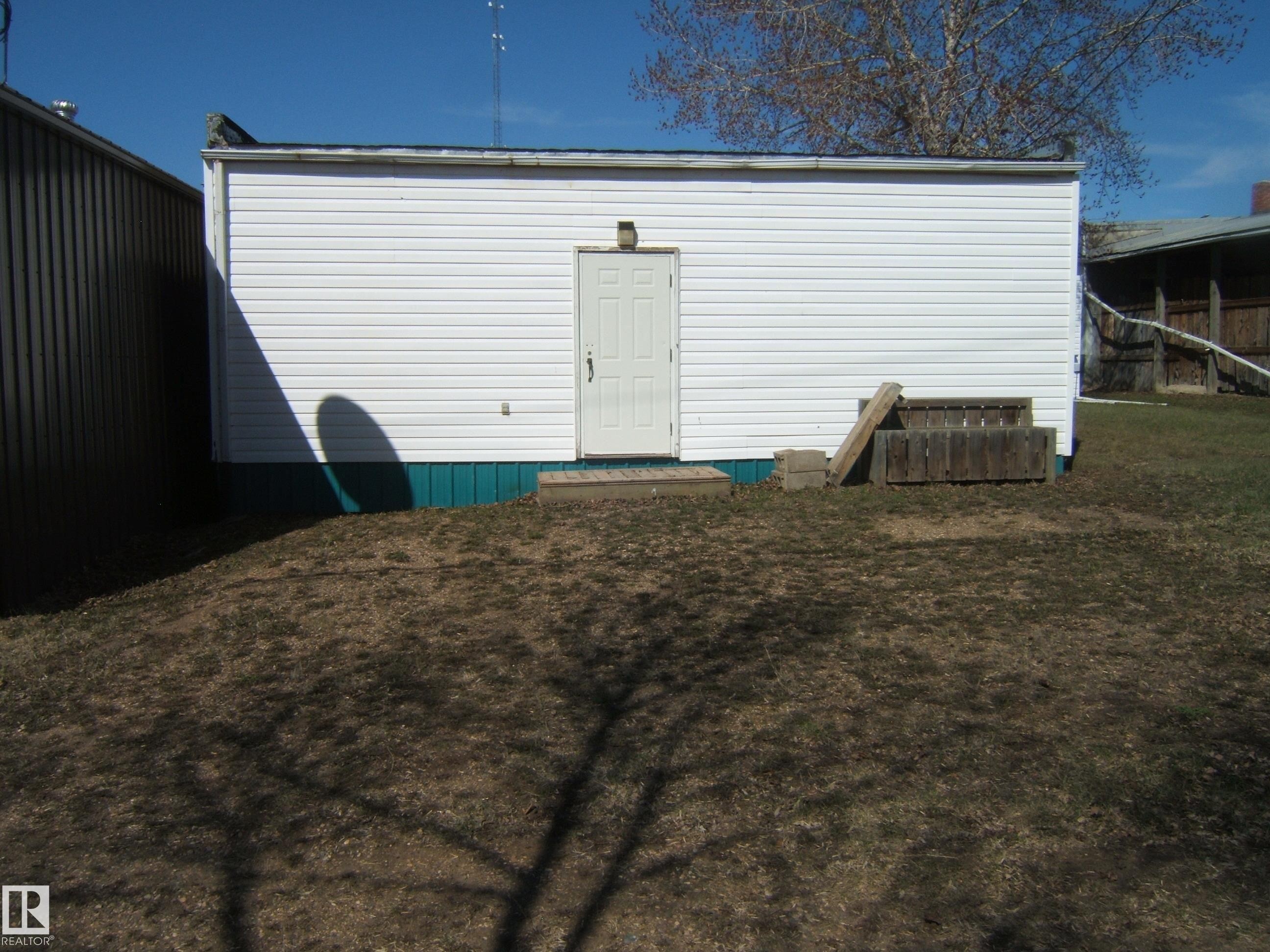 White vinyl siding exterior with a concrete stoop and teal foundation trim - 4707 50 Street, Two Hills, AB - Outdoor
