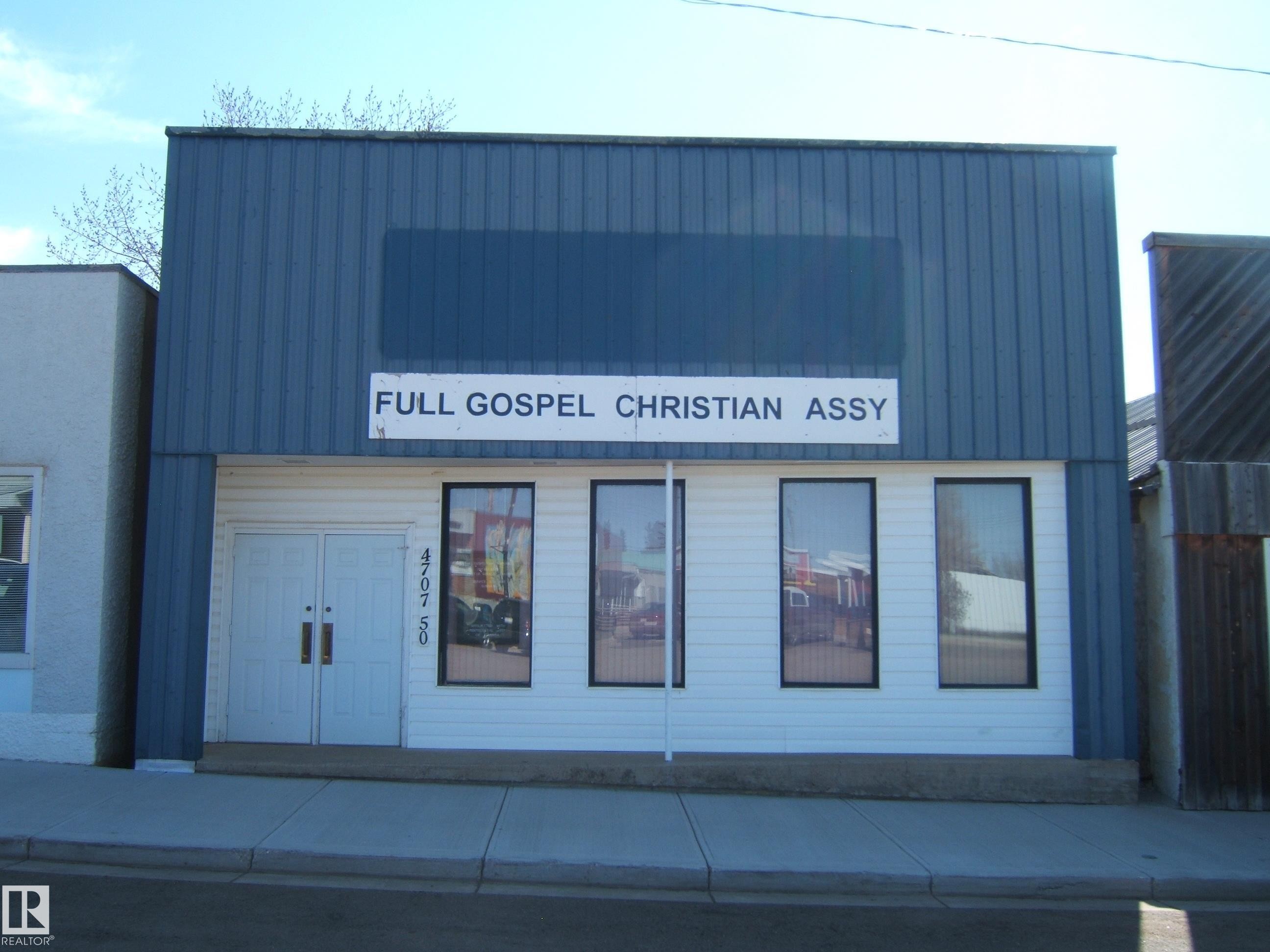 Commercial building featuring a blue corrugated metal facade over a white lower level - 4707 50 Street, Two Hills, AB - Outdoor