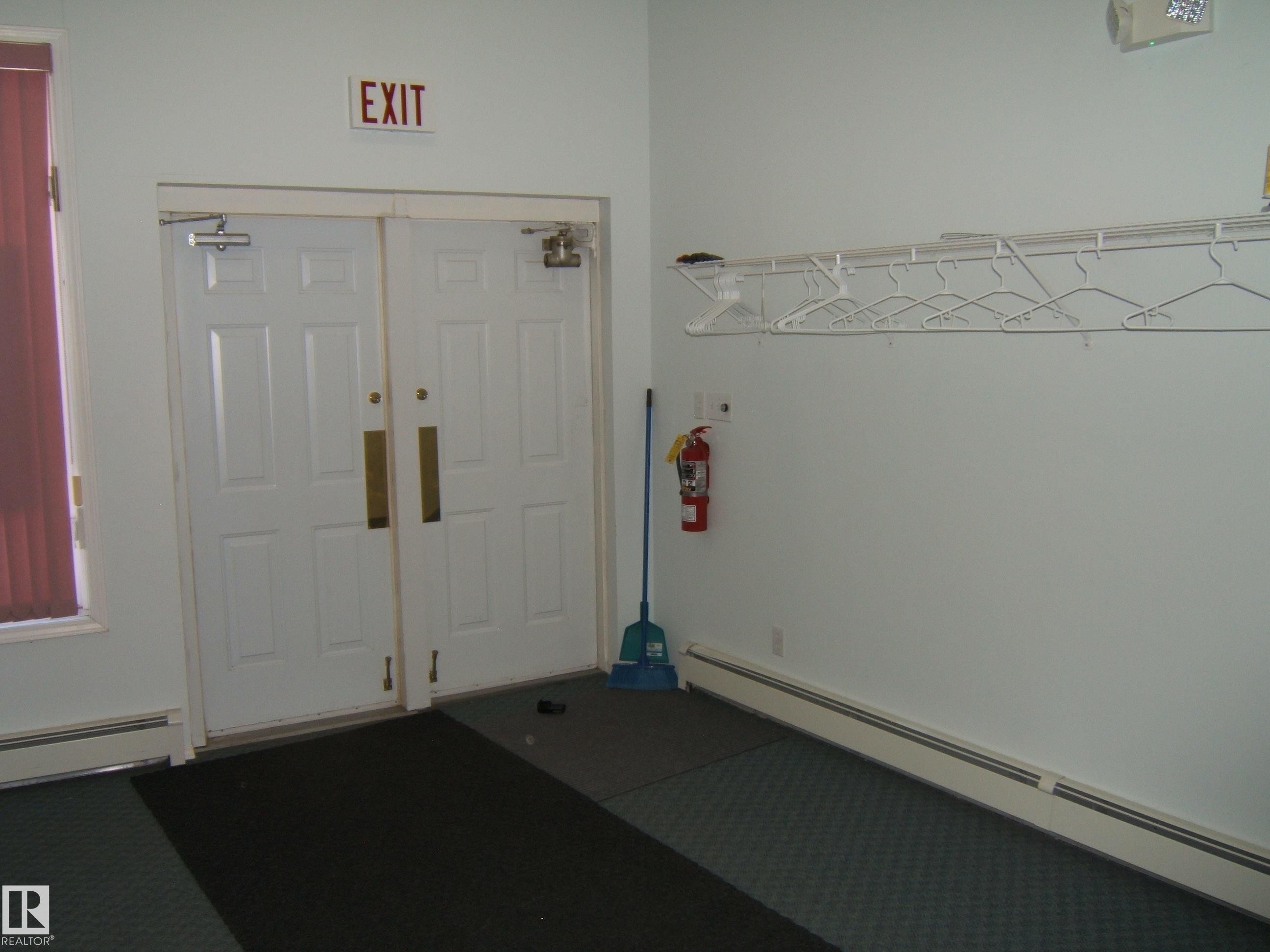 Double panel doors with brass pull handles and overhead door closers - 4707 50 Street, Two Hills, AB - Indoor Photo Showing Other Room