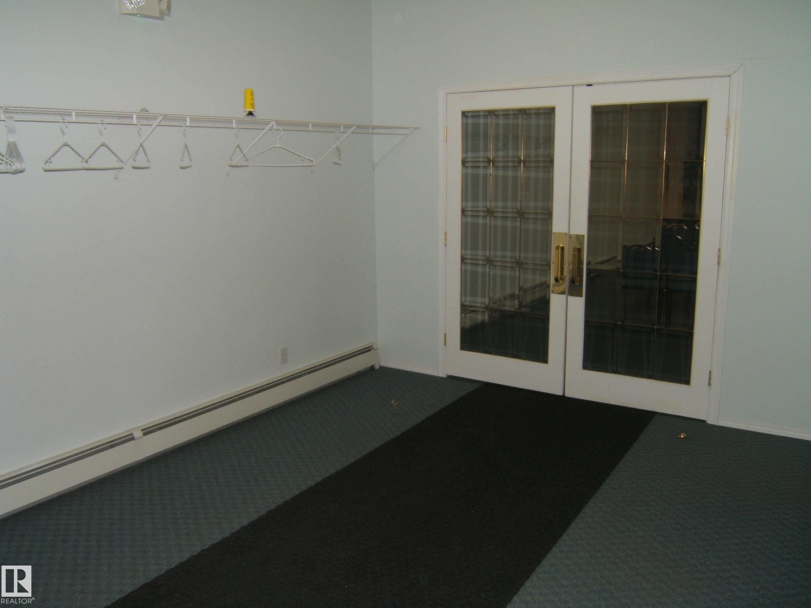 Double glass-paneled doors with brass hardware - 4707 50 Street, Two Hills, AB - Indoor Photo Showing Other Room