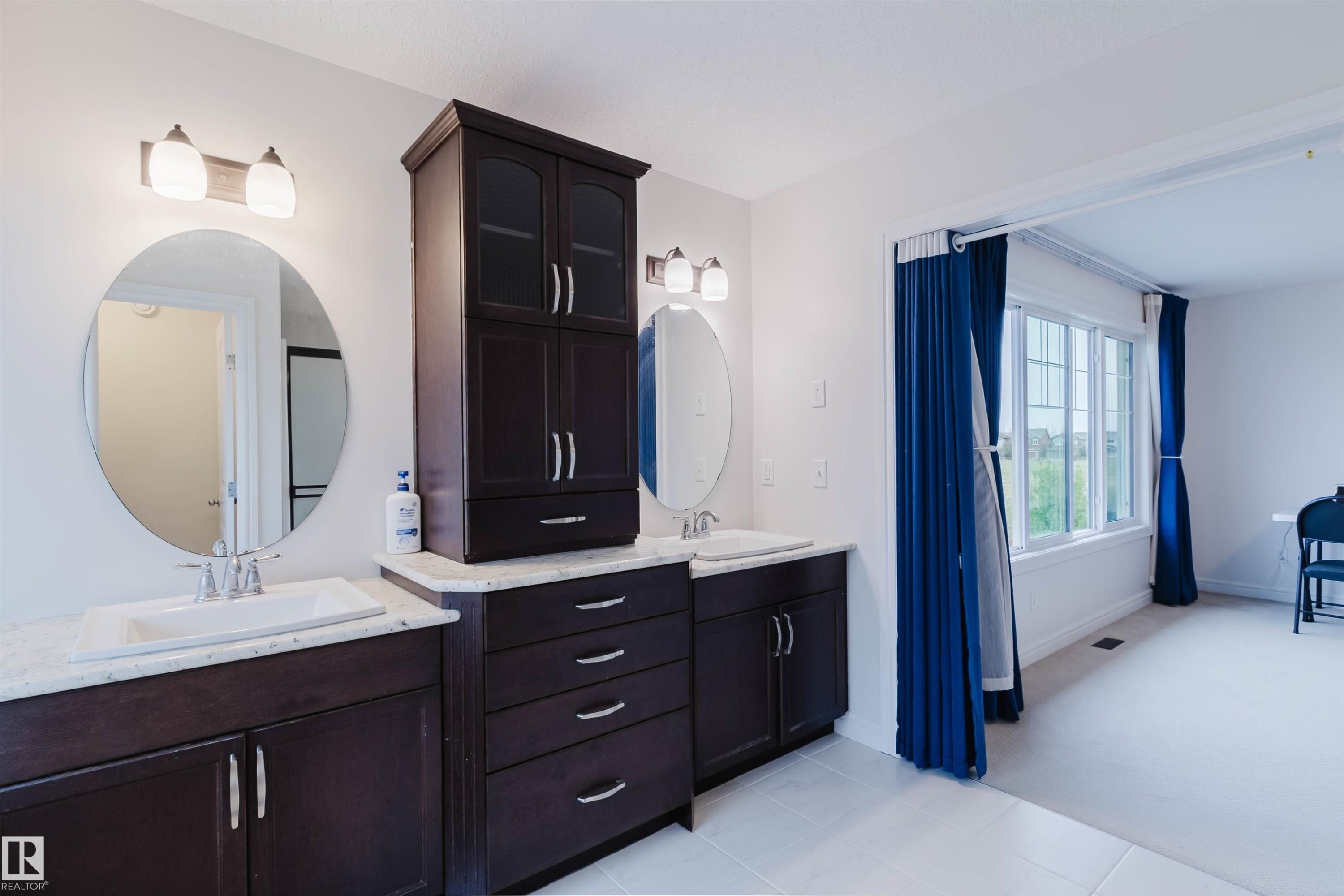 Double vanity with dark wood-finish cabinetry, white countertop, and under-mount sinks - 17718 5A Avenue, Edmonton, AB - Indoor Photo Showing Bathroom