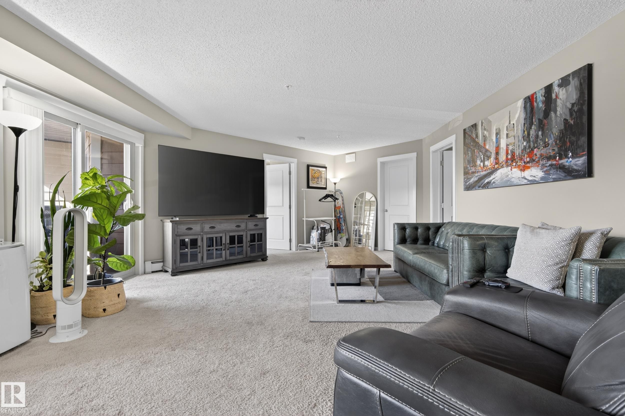 Spacious living area featuring light-toned carpet flooring, neutral wall paint, and white trim - 314 3211 James Mowatt Trail Sw, Edmonton, AB - Indoor Photo Showing Living Room