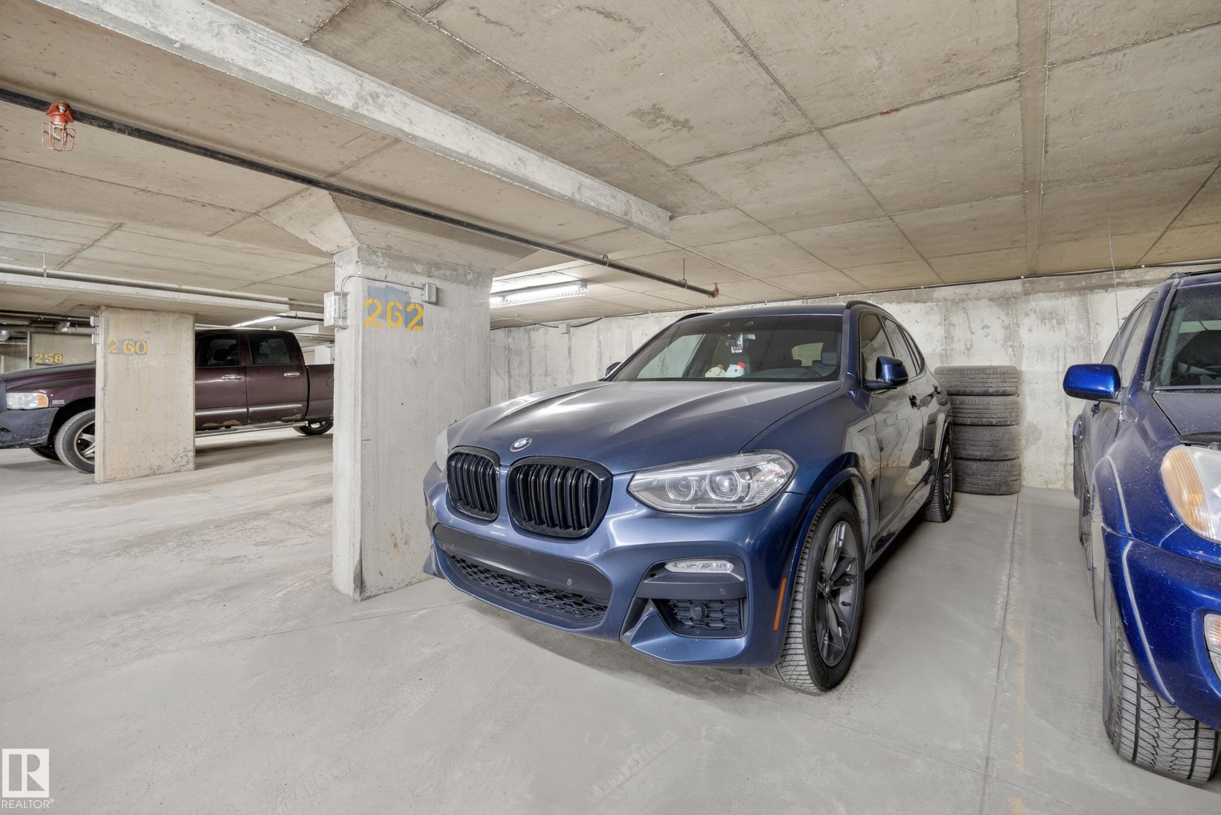 Underground parking garage featuring concrete walls and ceilings, designated parking spaces, and exposed utility piping - 314 3211 James Mowatt Trail Sw, Edmonton, AB - Indoor Photo Showing Garage