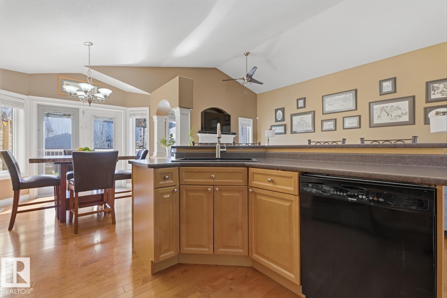Kitchen featuring wood-finish flooring, light-toned cabinetry, a black dishwasher, and a breakfast bar - 9 Danfield Place, Spruce Grove, AB - Indoor