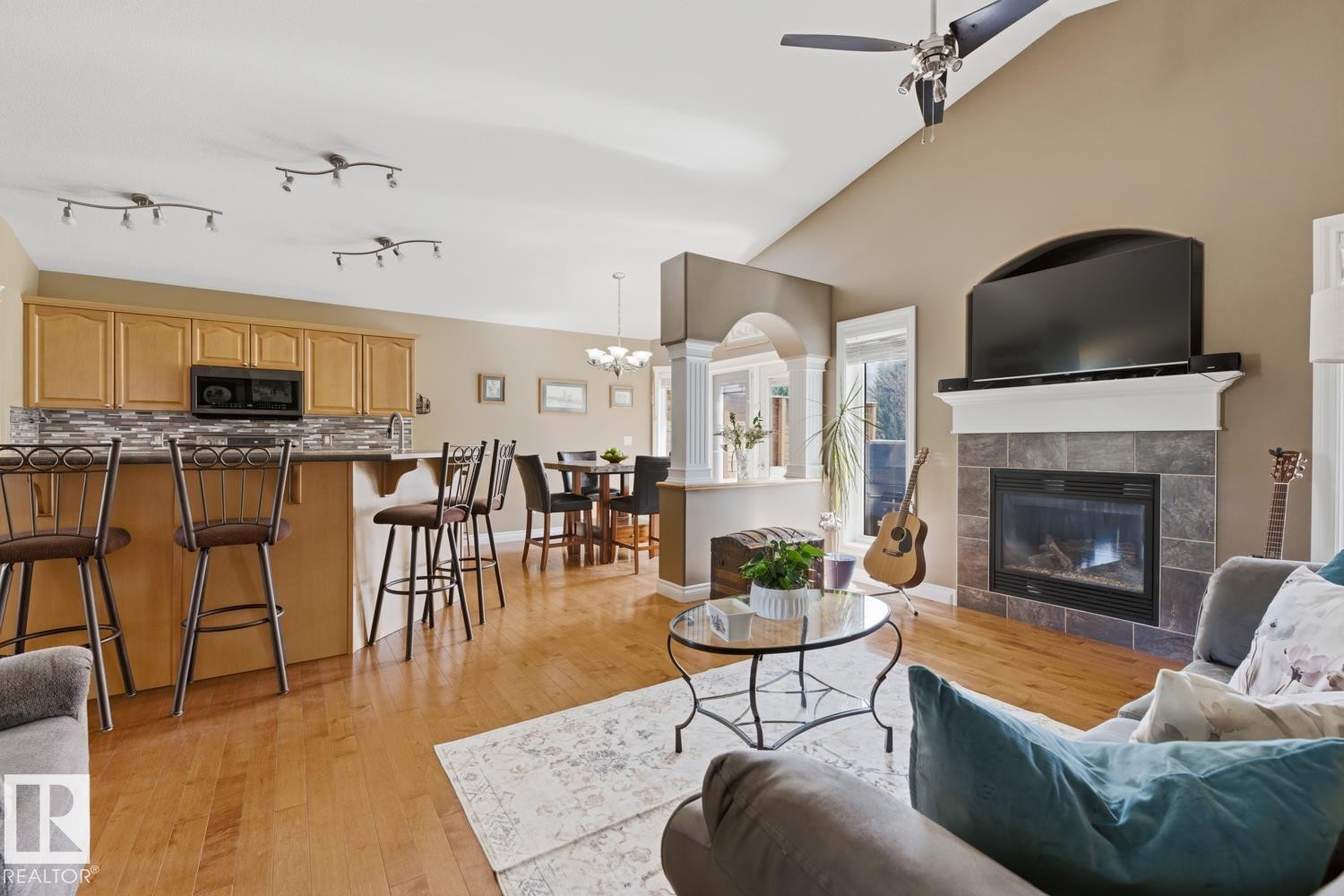 Spacious living area featuring light wood-finish flooring, a vaulted ceiling, and a fireplace with a stone tile surround and white mantel - 9 Danfield Place, Spruce Grove, AB - Indoor Photo Showing Living Room With Fireplace