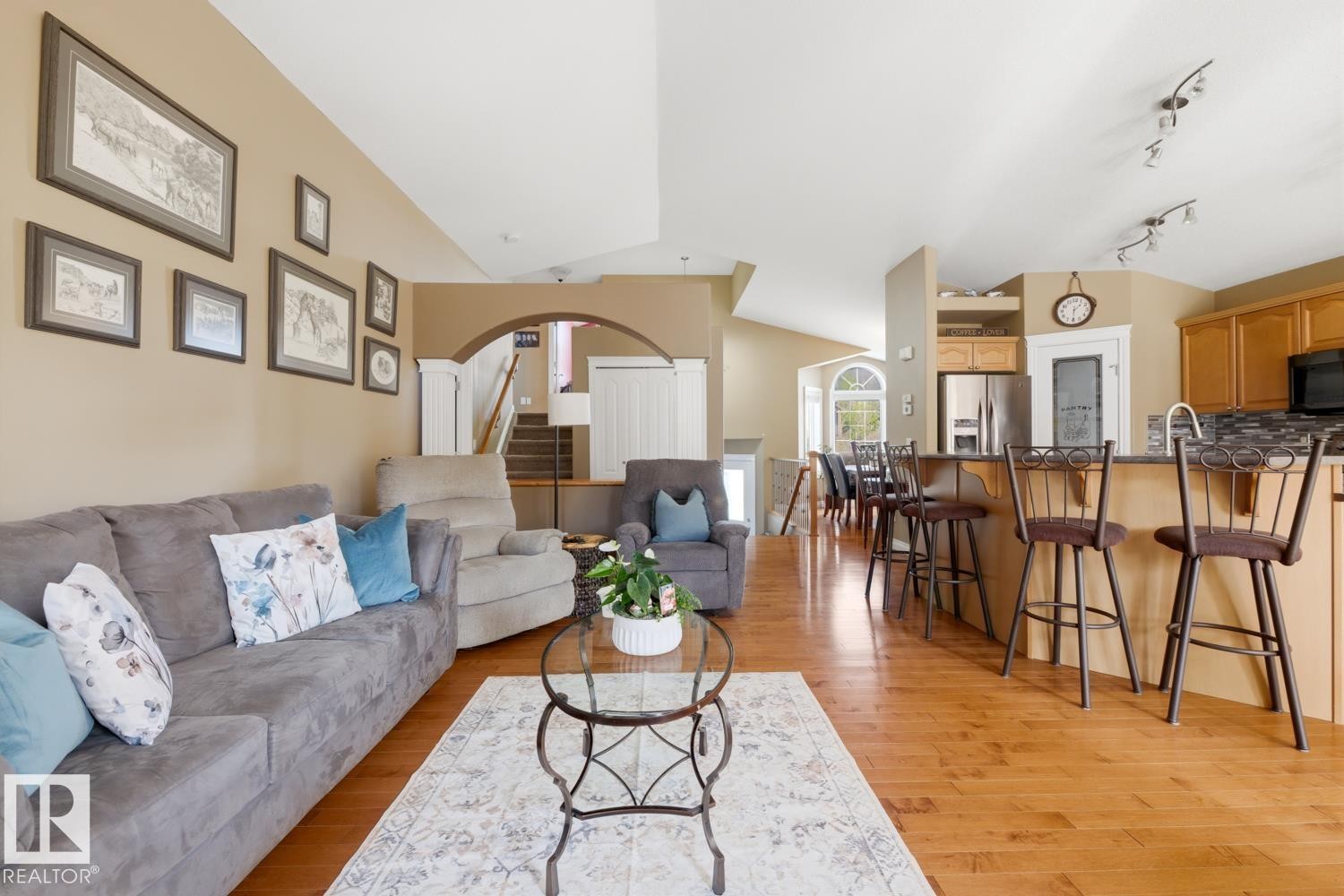 Open-concept living area featuring wood-finish flooring, vaulted ceilings, and a kitchen island with seating - 9 Danfield Place, Spruce Grove, AB - Indoor Photo Showing Living Room
