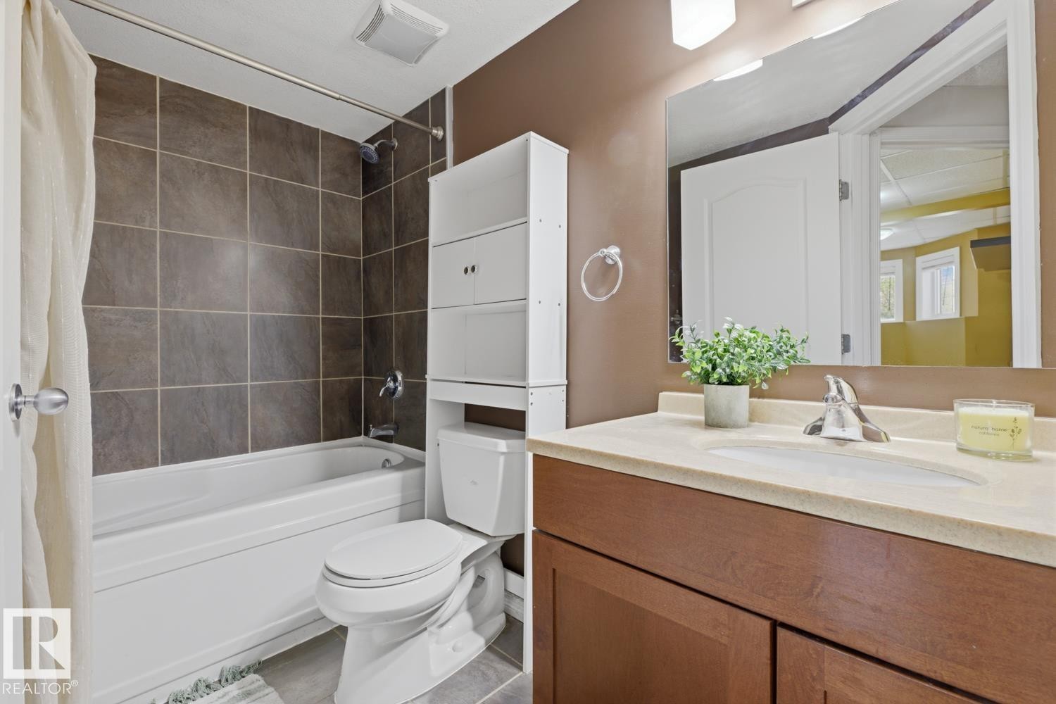 Bathroom featuring a built-in bathtub with shower, dark tile surround, a toilet, and a white storage unit - 9 Danfield Place, Spruce Grove, AB - Indoor Photo Showing Bathroom