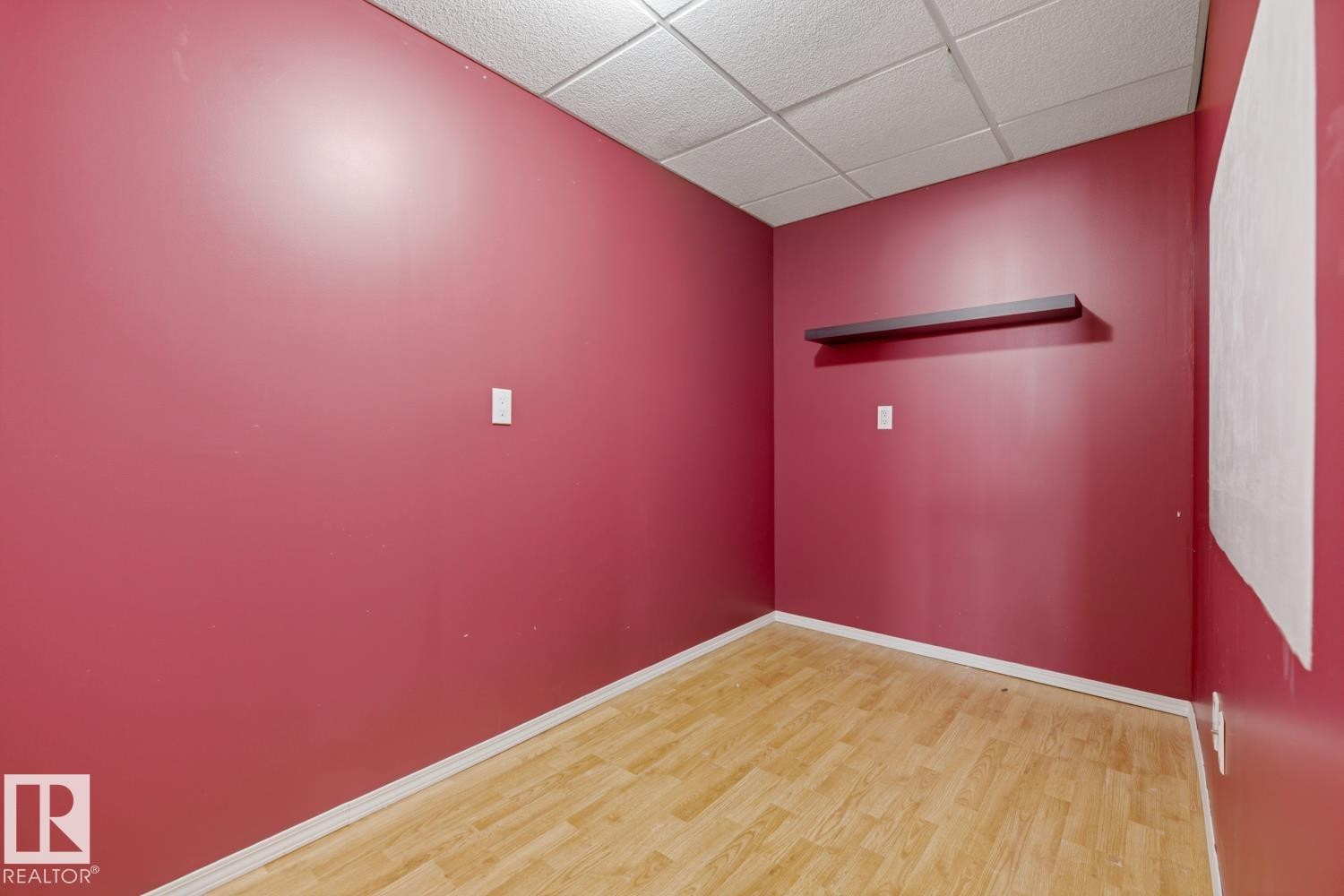 Room featuring bright red walls, wood-finish flooring, white baseboards, and a white grid ceiling - 9 Danfield Place, Spruce Grove, AB - Indoor Photo Showing Other Room