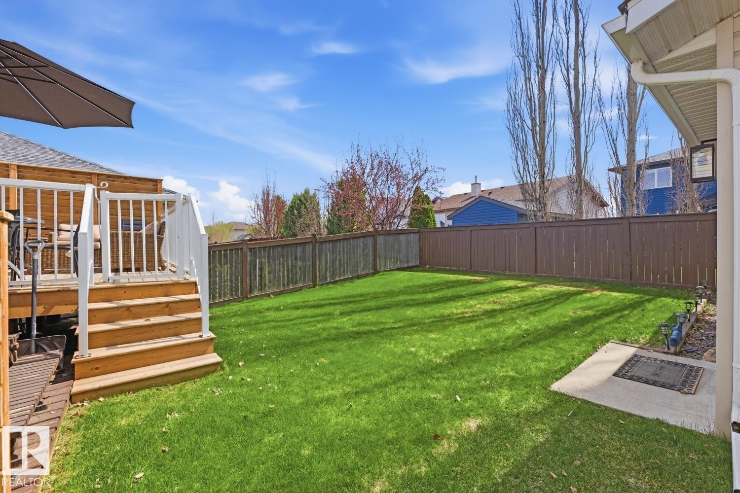 Expansive backyard featuring a manicured lawn, a multi-level wood deck with white railings, and a perimeter fence - 9 Danfield Place, Spruce Grove, AB - Outdoor