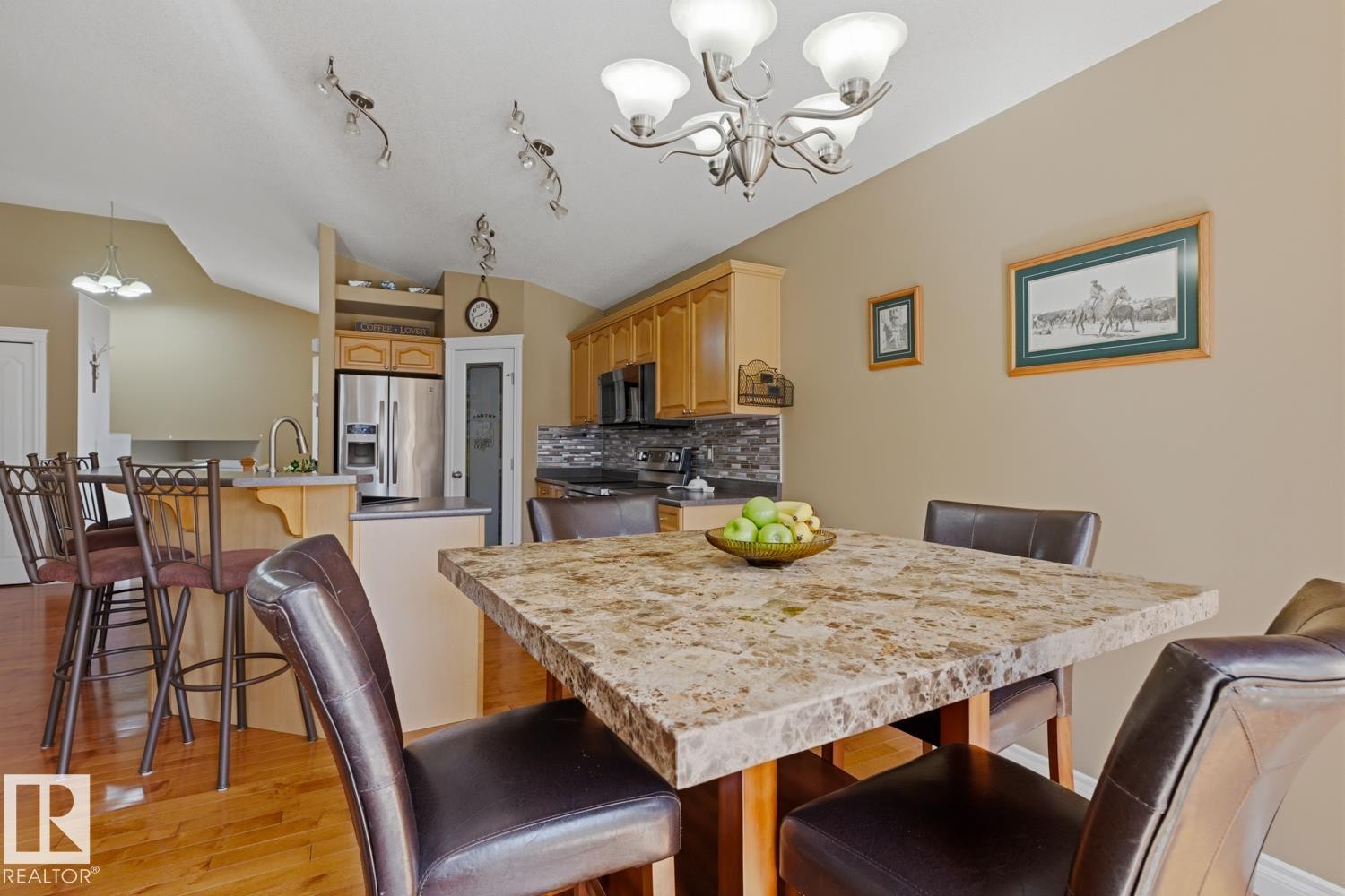 Dining area featuring a stone-look tabletop, hardwood-finish flooring, and a brushed nickel chandelier - 9 Danfield Place, Spruce Grove, AB - Indoor Photo Showing Dining Room