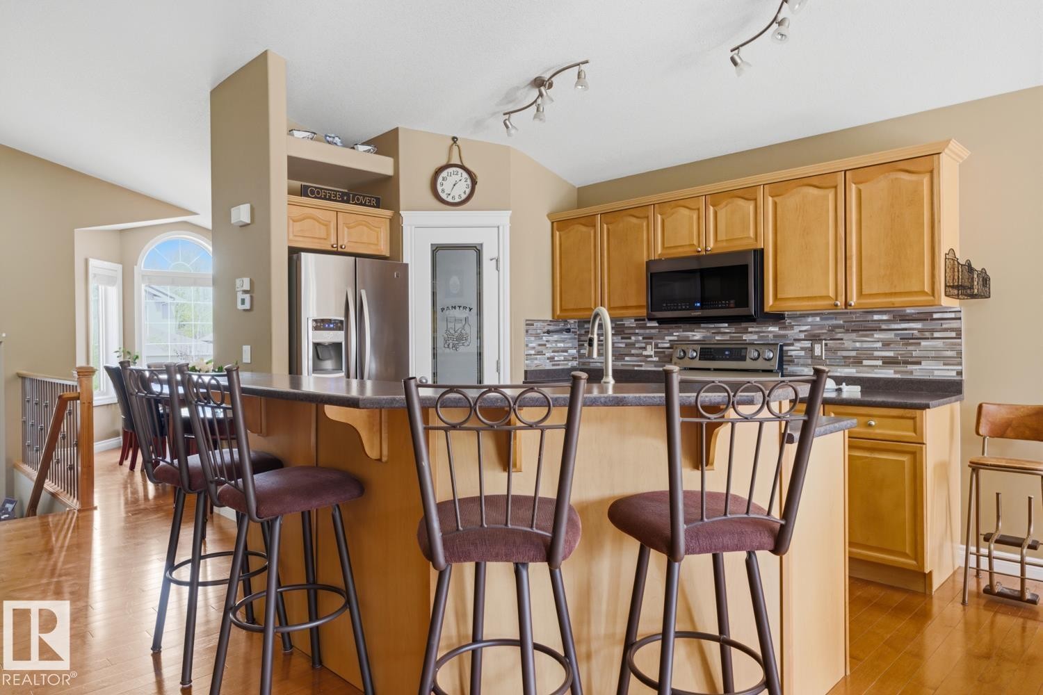 Kitchen featuring light-tone wood cabinetry, a dark countertop, and a mosaic tile backsplash - 9 Danfield Place, Spruce Grove, AB - Indoor Photo Showing Kitchen