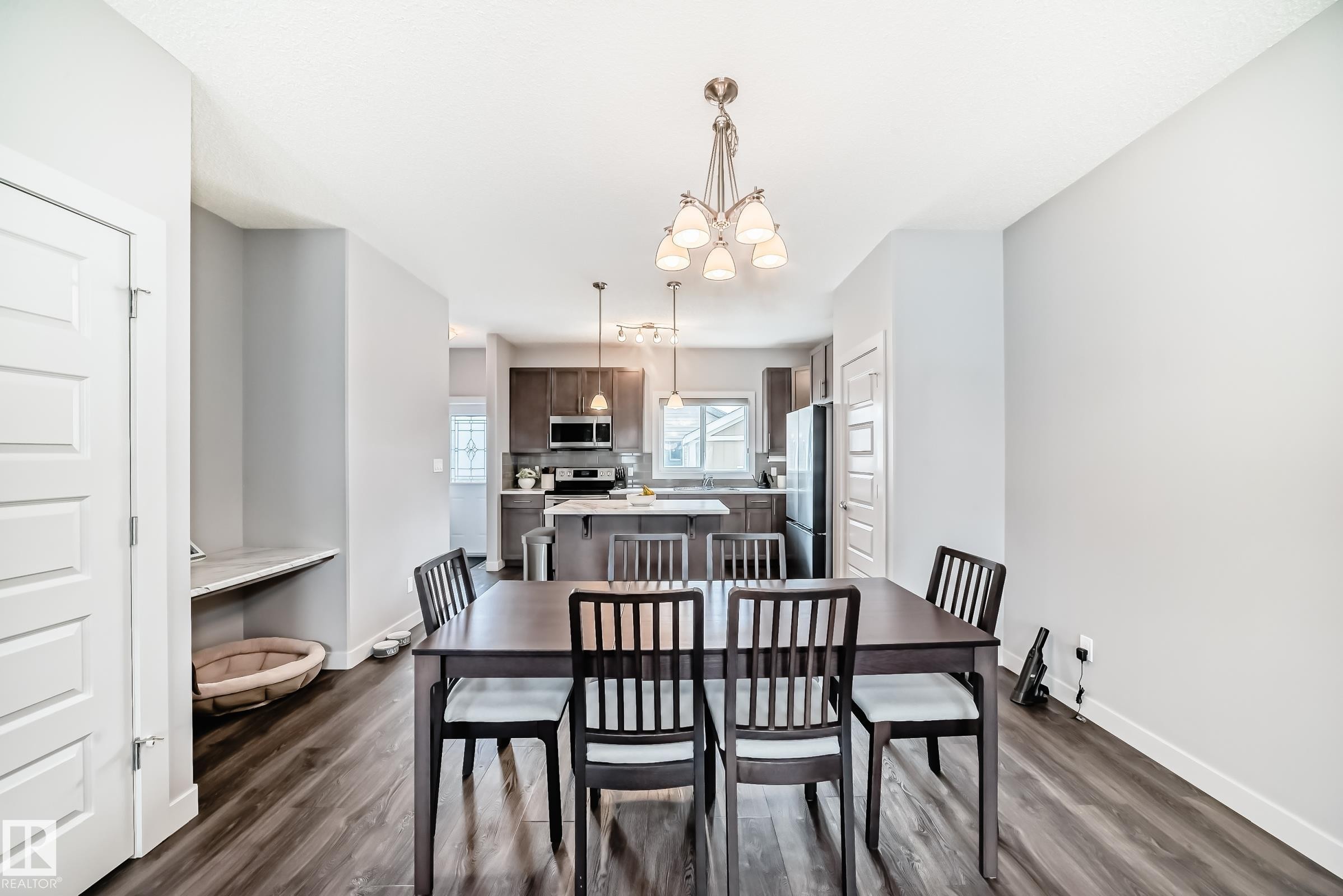 Open-concept living space featuring wood-finish flooring and a contemporary chandelier - 6919 Cardinal Wynd, Edmonton, AB - Indoor Photo Showing Dining Room