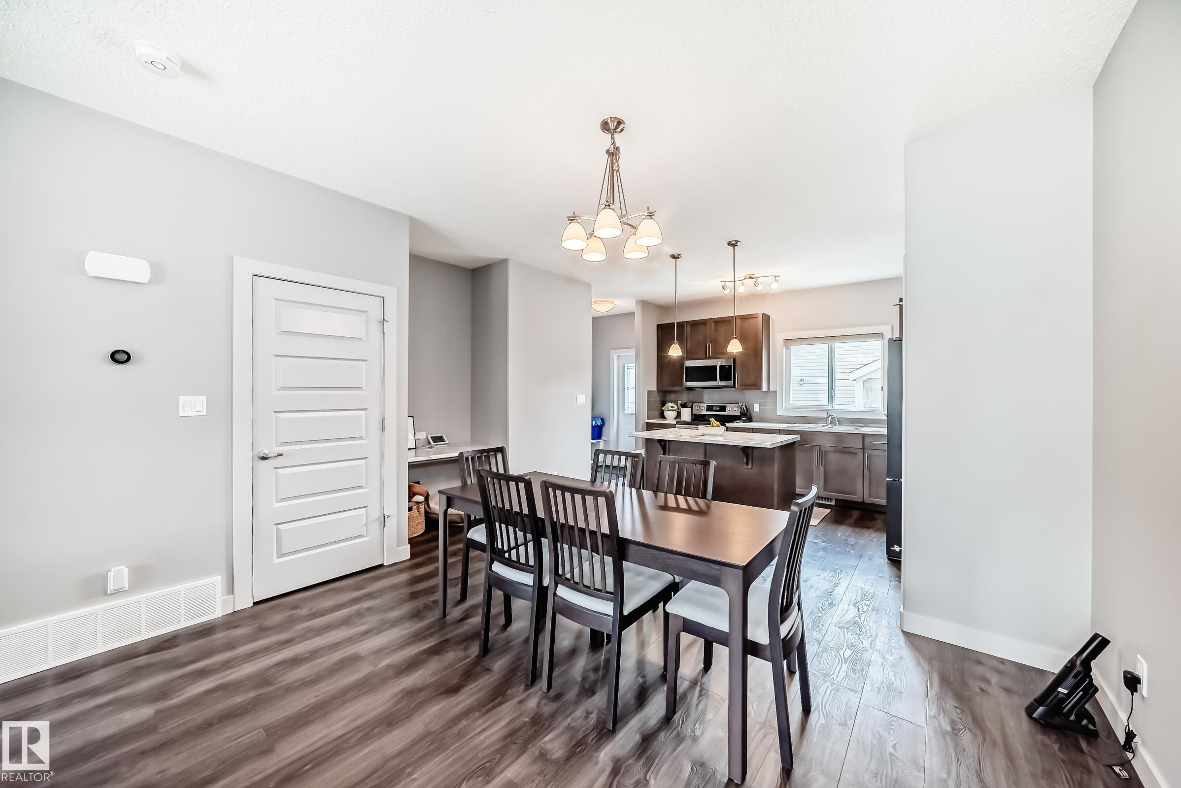 Open-concept dining area featuring wood-finish flooring, a contemporary chandelier - 6919 Cardinal Wynd, Edmonton, AB - Indoor