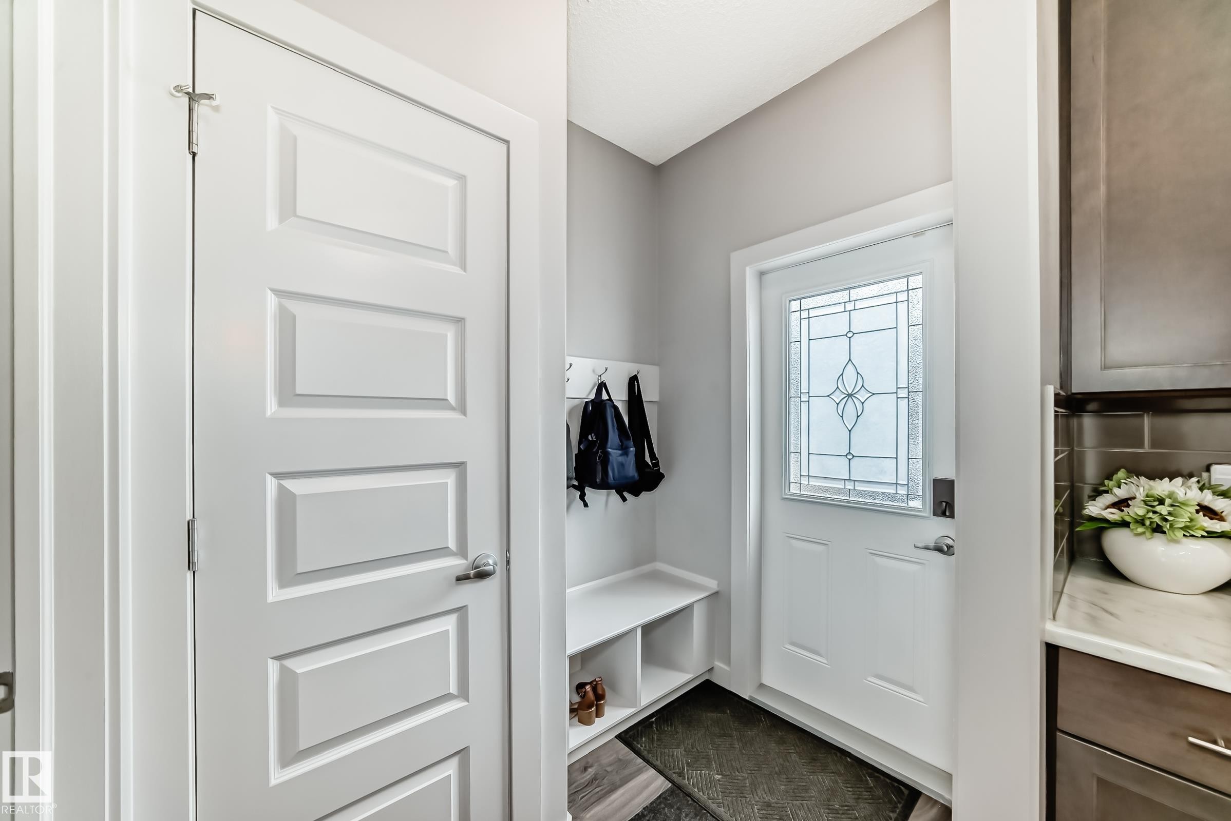 Entryway featuring a decorative glass panel door, built-in bench with storage cubbies, and coat hooks - 6919 Cardinal Wynd, Edmonton, AB - Indoor Photo Showing Other Room