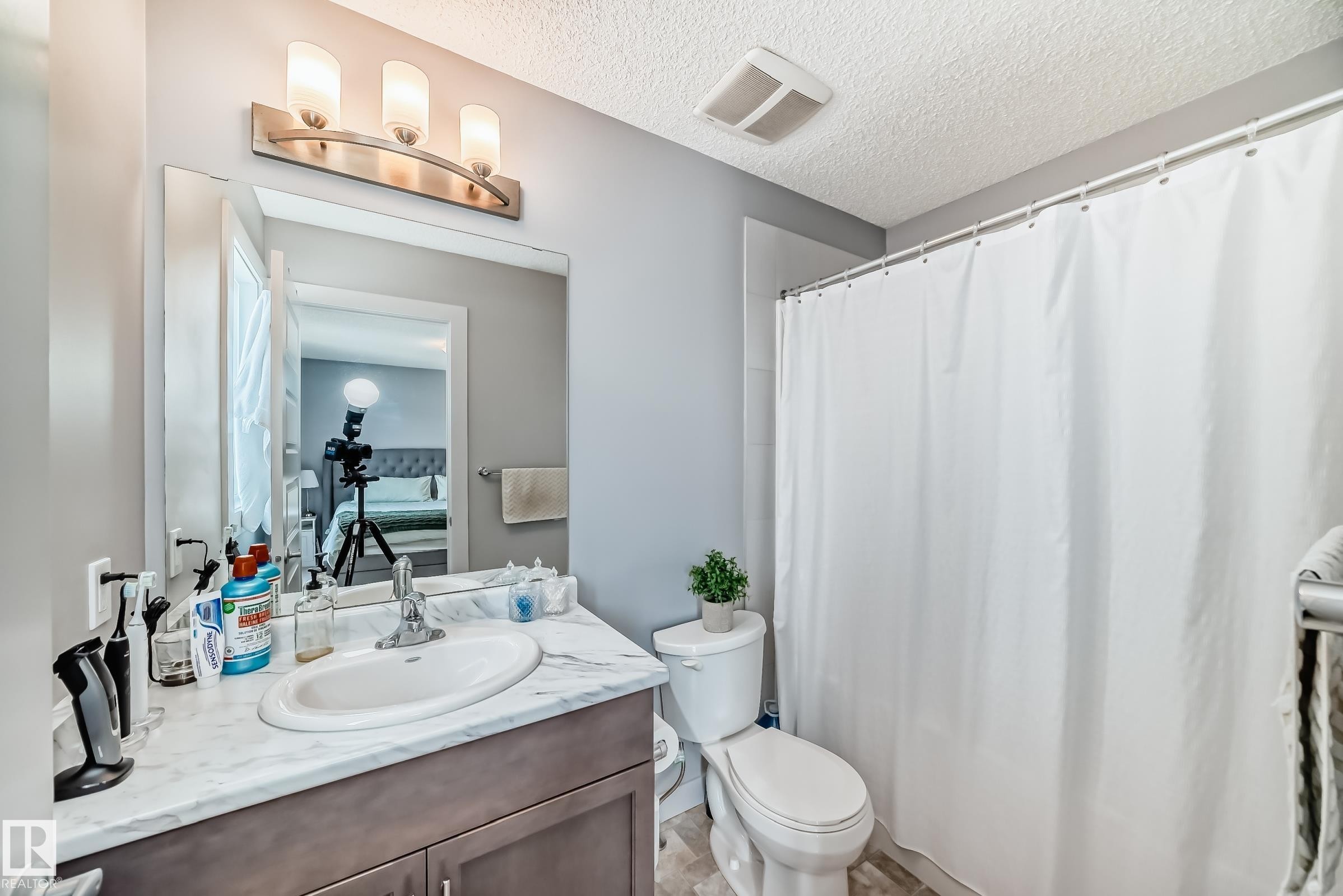 Primary Bathroom vanity featuring a single basin sink, light-toned countertop, and wood-finish cabinetry - 6919 Cardinal Wynd, Edmonton, AB - Indoor Photo Showing Bathroom