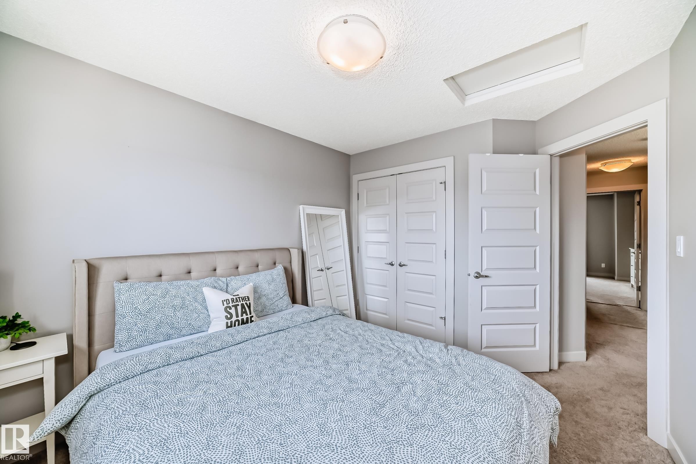 Bedroom featuring soft gray walls, a textured ceiling, a flush-mount light fixture, and a built-in closet with paneled bifold doors - 6919 Cardinal Wynd, Edmonton, AB - Indoor Photo Showing Bedroom