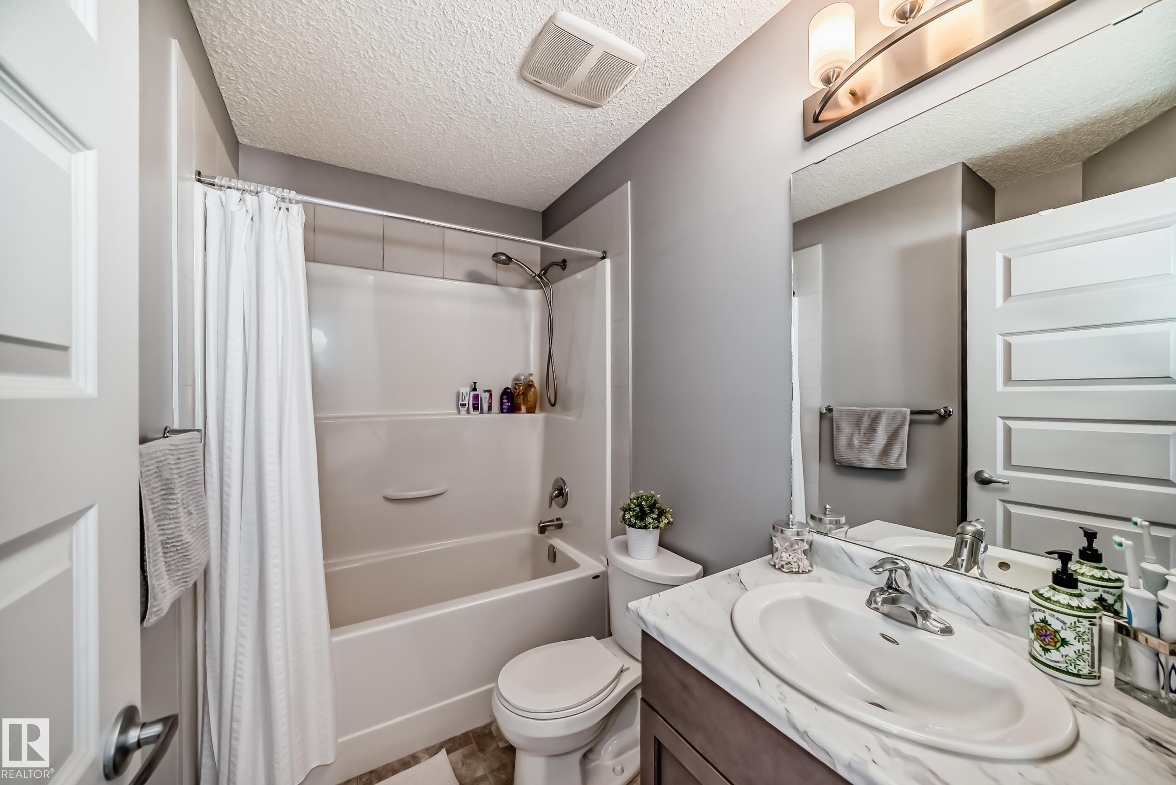 Bathroom featuring a white bathtub/shower combination, vanity with a white oval sink, chrome faucet - 6919 Cardinal Wynd, Edmonton, AB - Indoor Photo Showing Bathroom