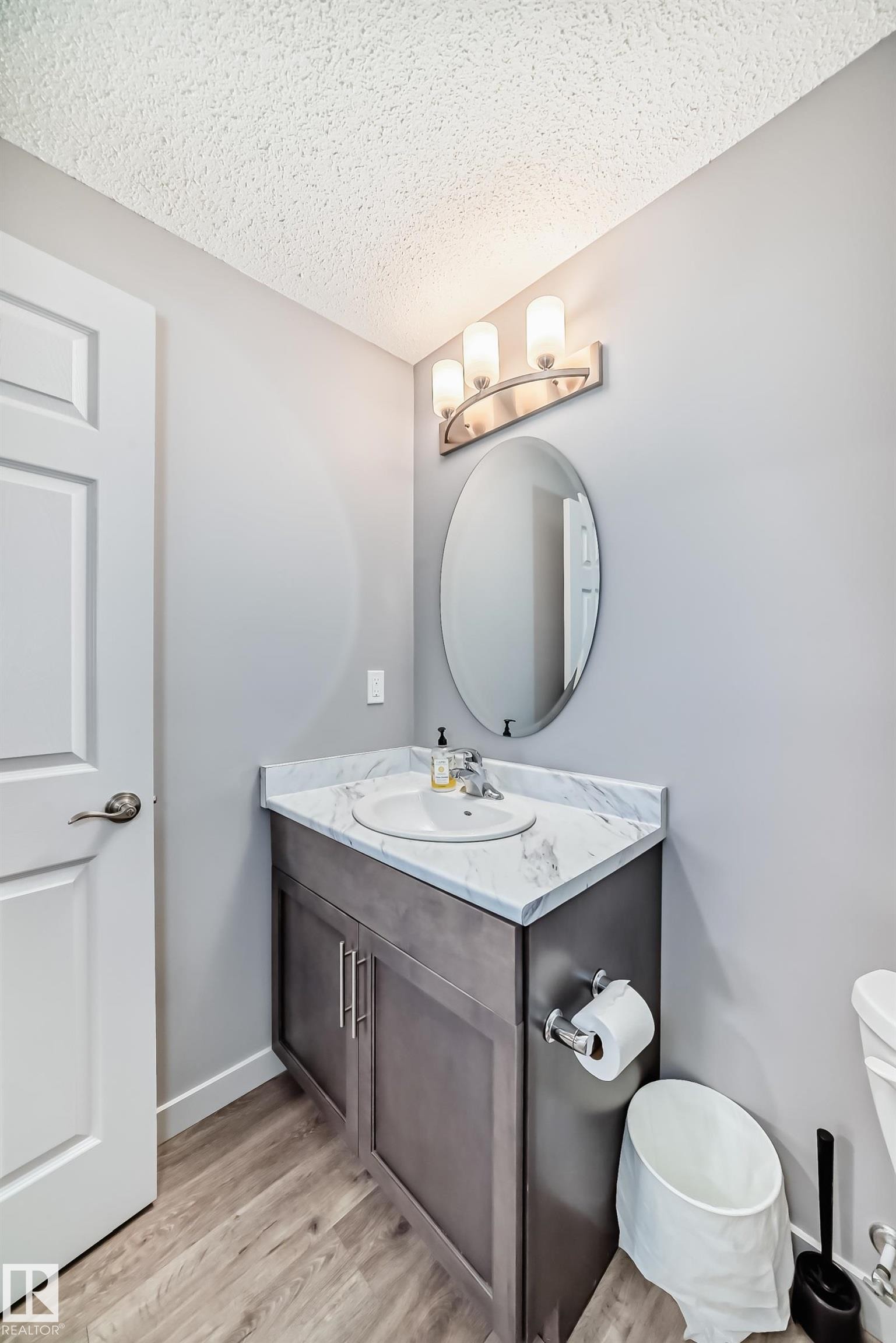 Bathroom vanity featuring a white oval undermount sink, and a dark wood-finish cabinet with brushed nickel hardware - 6919 Cardinal Wynd, Edmonton, AB - Indoor Photo Showing Bathroom