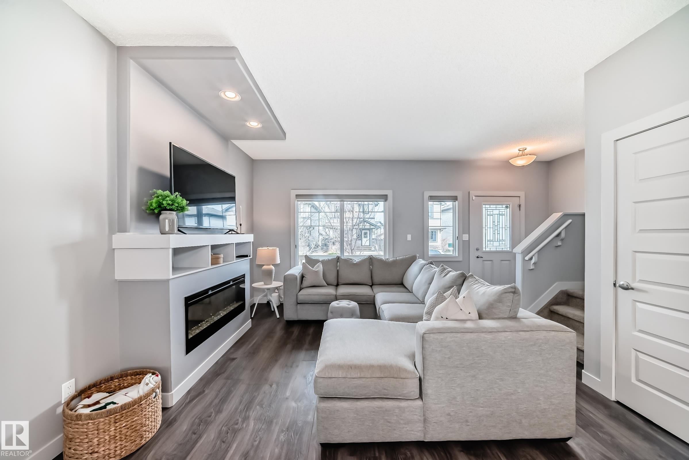Spacious living area featuring an integrated media wall with an electric fireplace, recessed lighting, and shelving - 6919 Cardinal Wynd, Edmonton, AB - Indoor Photo Showing Living Room With Fireplace