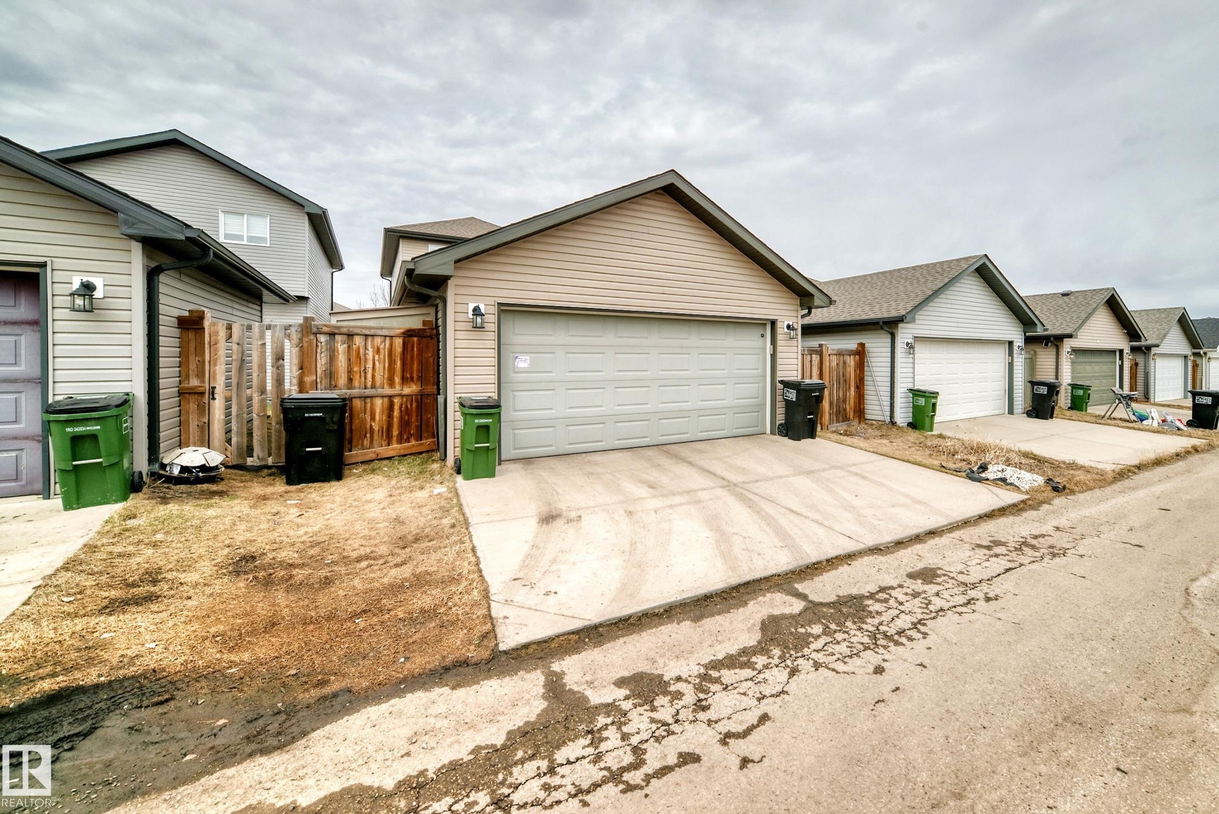 Exterior featuring beige horizontal siding and a light gray garage door - 6919 Cardinal Wynd, Edmonton, AB - Outdoor