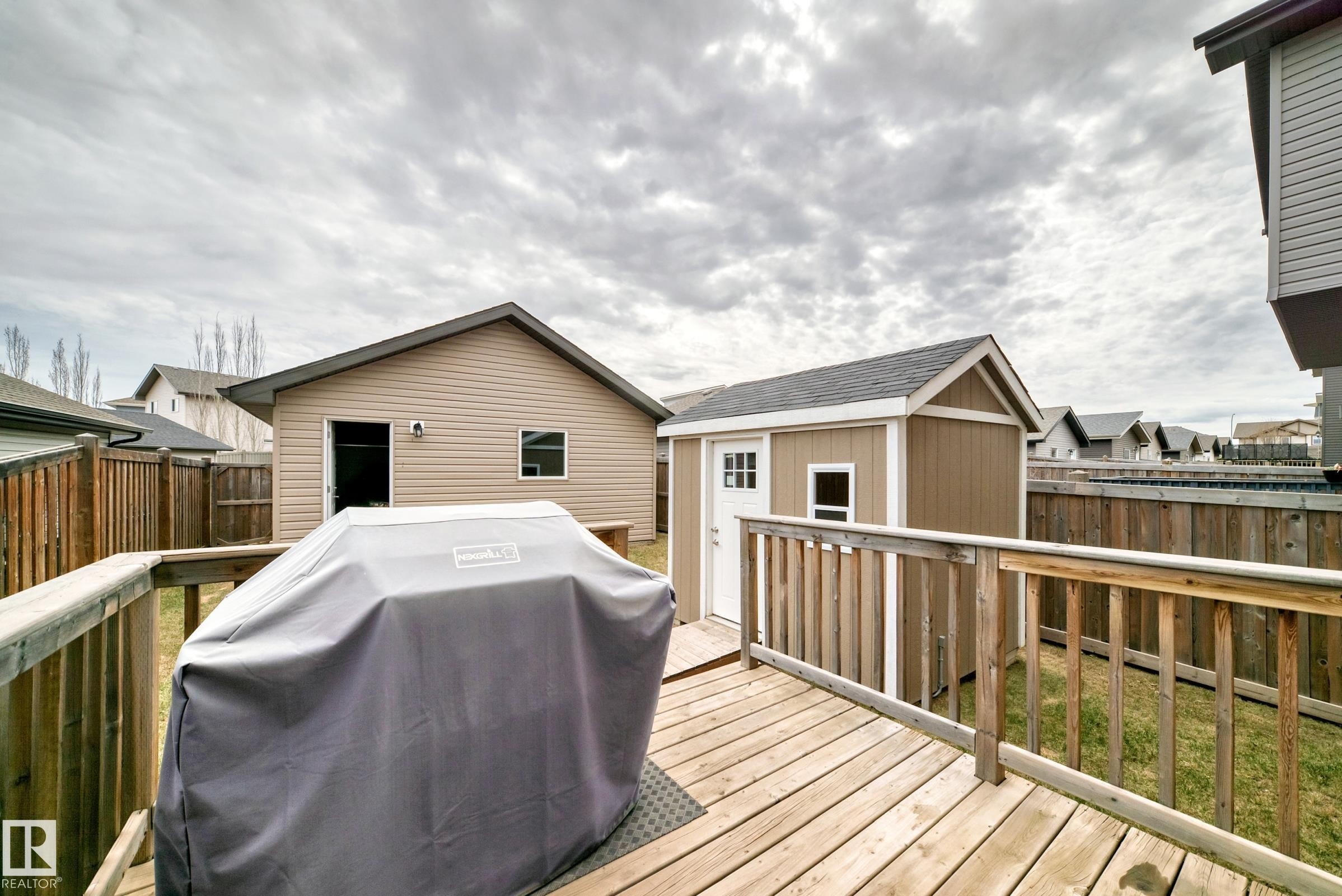 Spacious wooden deck with a matching shed featuring a white door and small window - 6919 Cardinal Wynd, Edmonton, AB - Outdoor With Deck Patio Veranda With Exterior