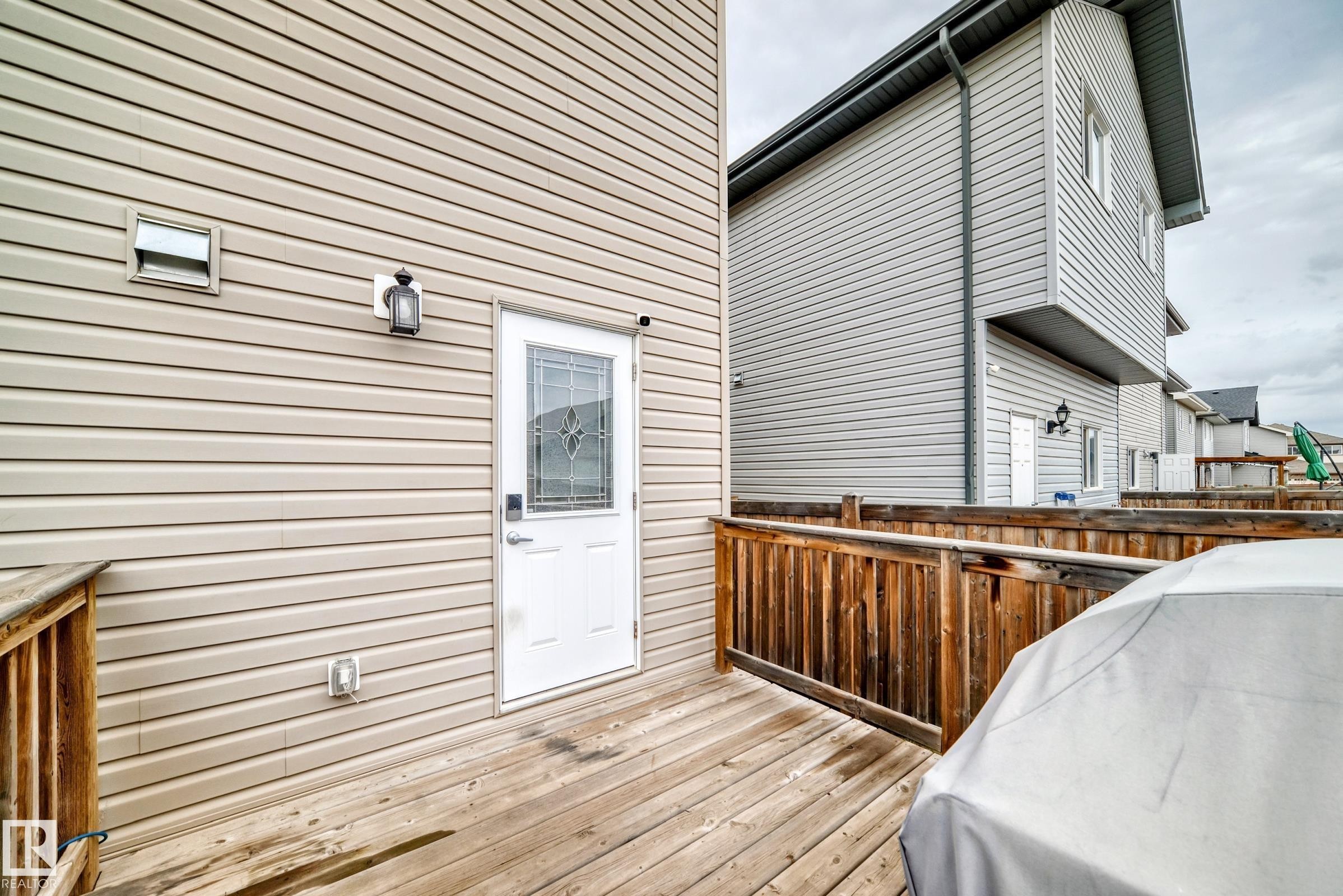 Outdoor wood-finish deck featuring a wood railing and light-colored horizontal siding - 6919 Cardinal Wynd, Edmonton, AB - Outdoor With Deck Patio Veranda With Exterior