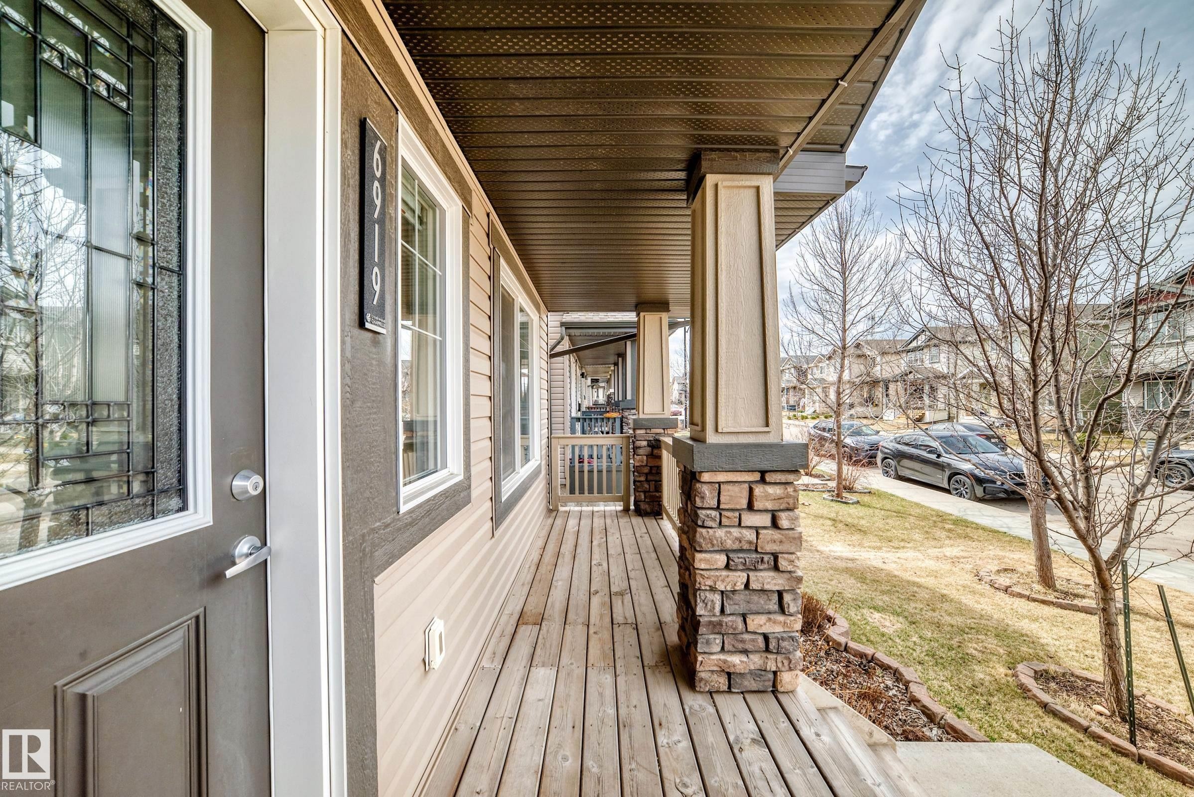Covered front porch featuring a wood-finish floor and stone-clad pillars - 6919 Cardinal Wynd, Edmonton, AB - Outdoor With Deck Patio Veranda With Exterior