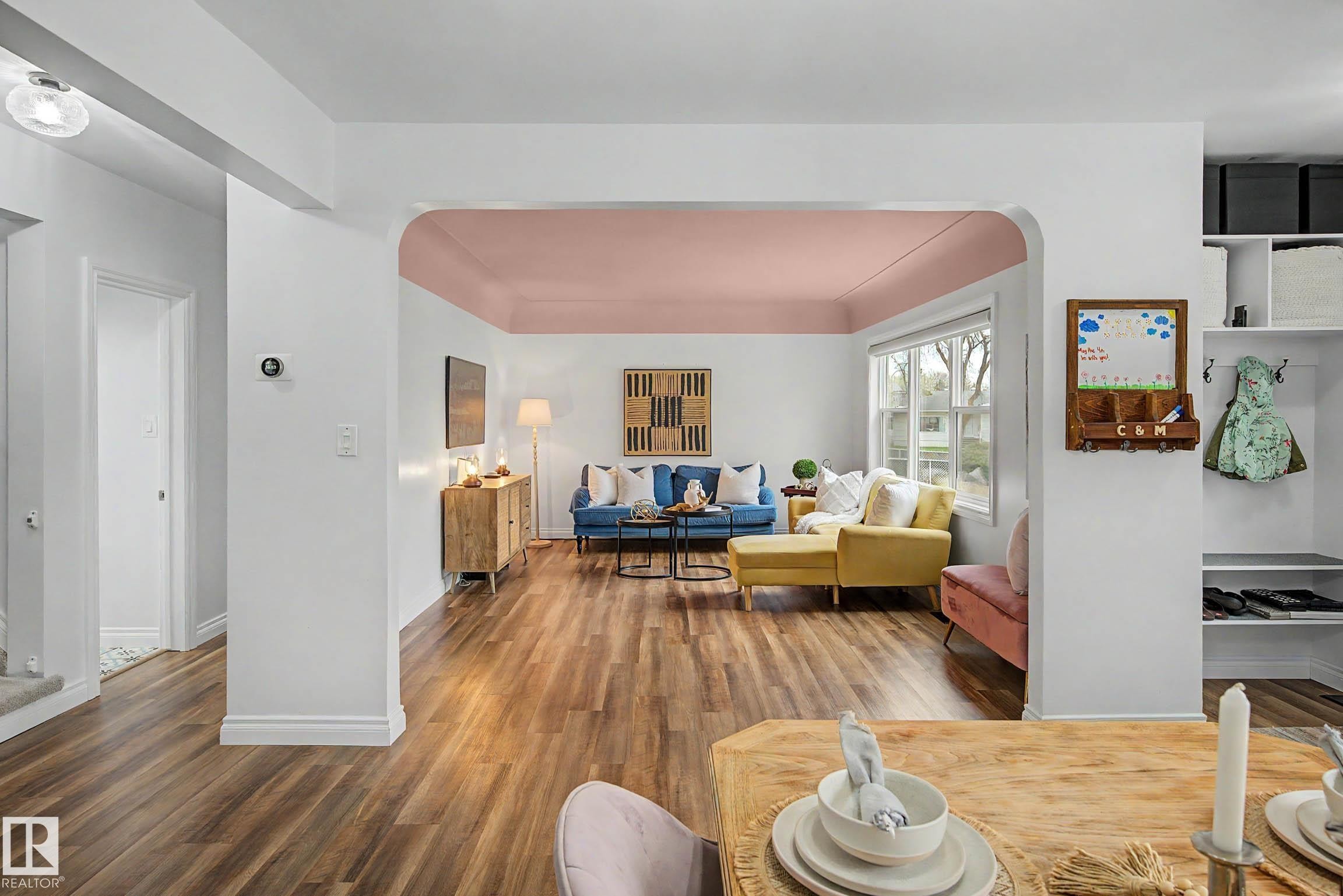 Archway entry leading to a living area with wood-finish flooring, a tray ceiling, and a large window - 13316 109A Avenue, Edmonton, AB - Indoor Photo Showing Living Room