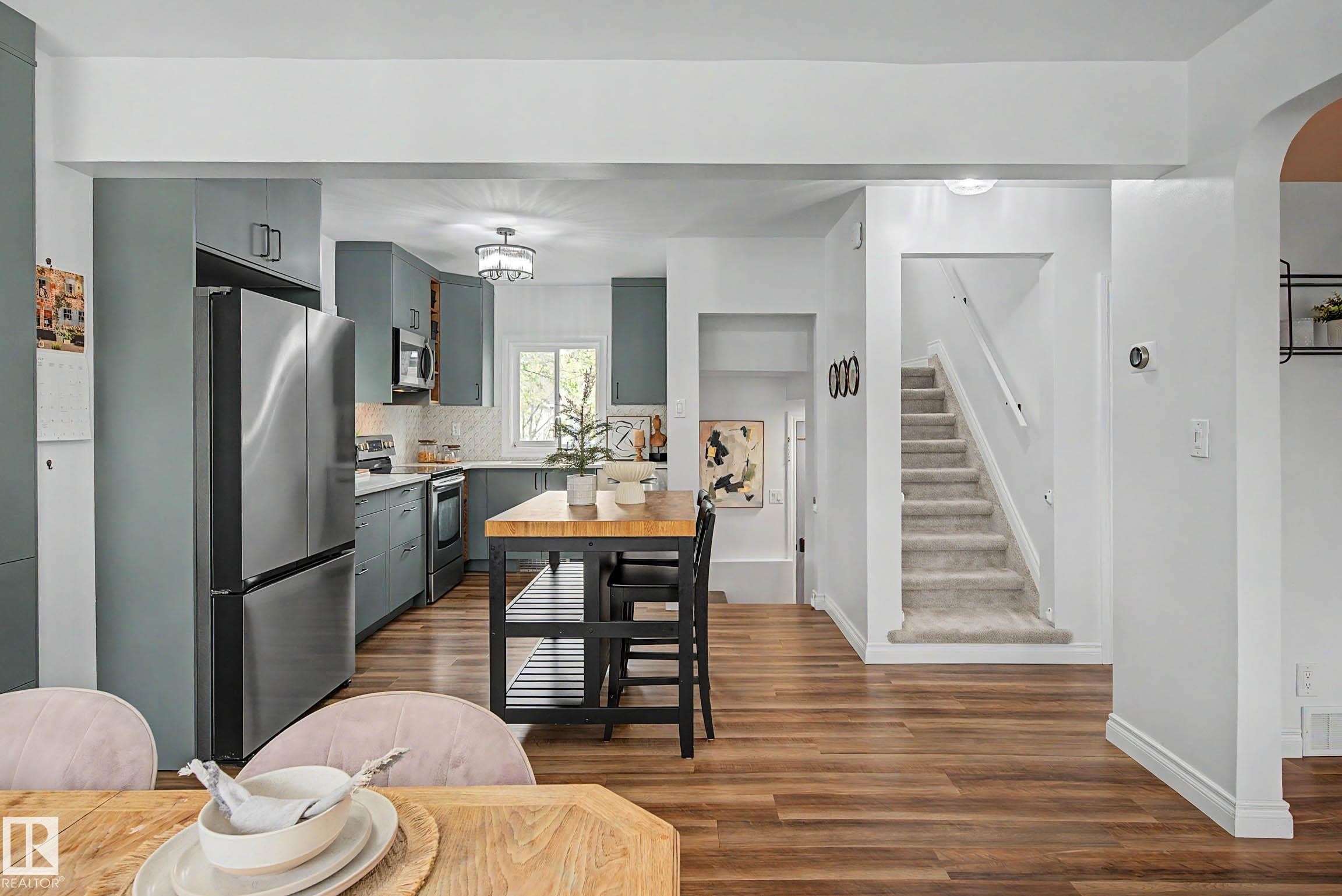 Kitchen featuring wood-finish flooring, stainless steel appliances, blue-gray cabinetry, and a butcher block island - 13316 109A Avenue, Edmonton, AB - Indoor