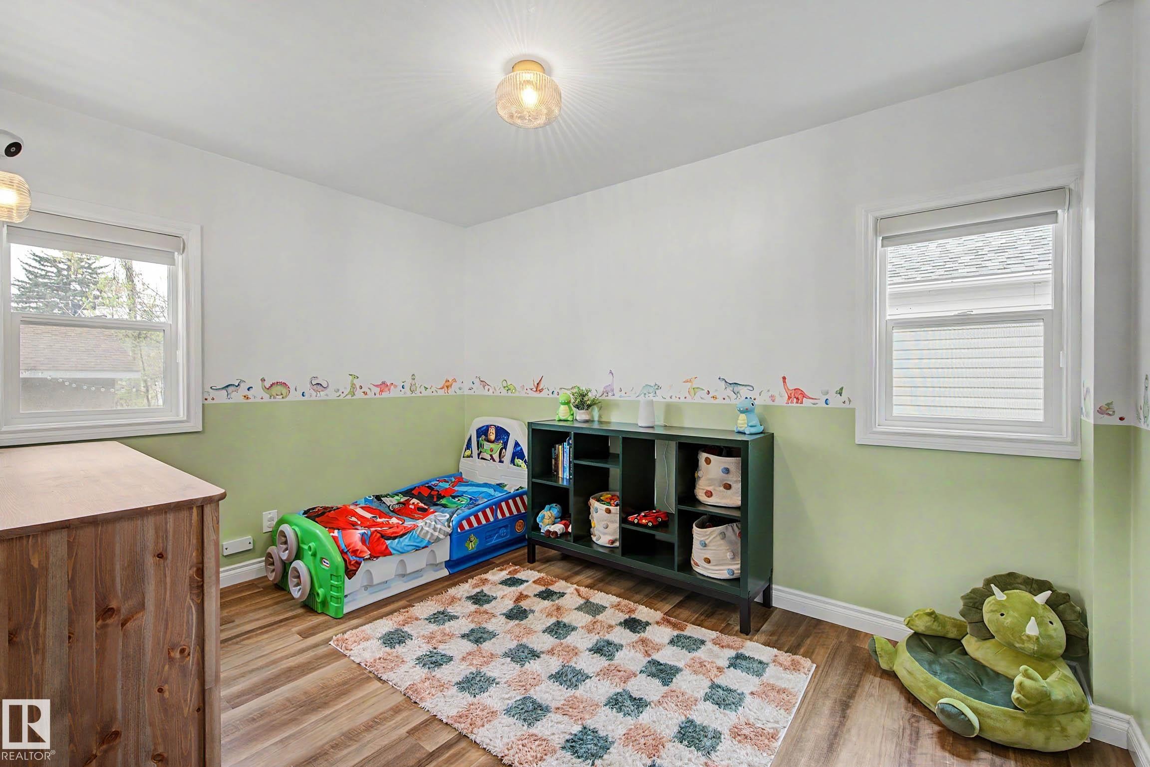 Room featuring wood-finish flooring, two window openings, and two ceiling-mounted light fixtures - 13316 109A Avenue, Edmonton, AB - Indoor