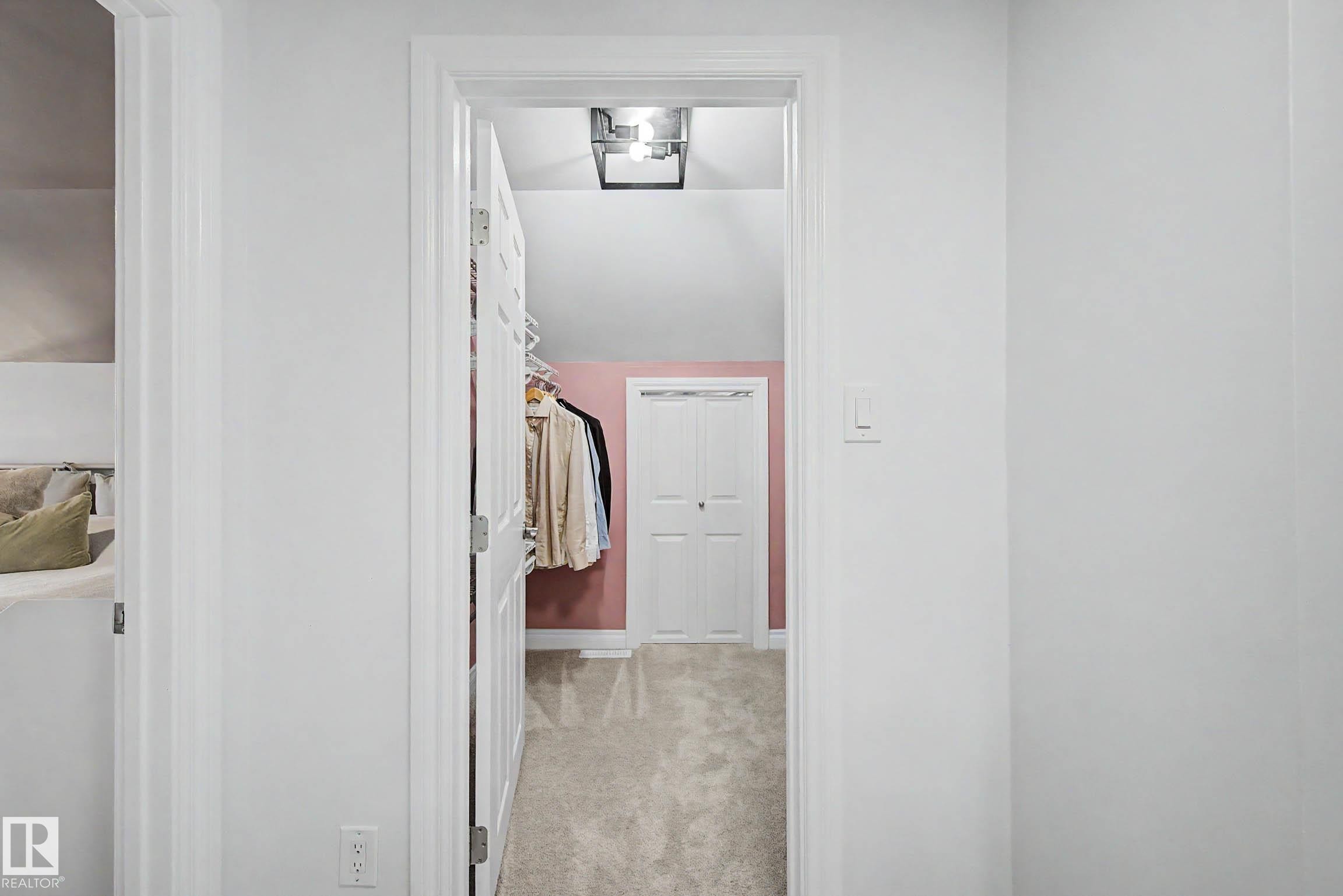 Hallway with white walls and trim, leading to a closet with sloped ceilings and light-colored carpeting - 13316 109A Avenue, Edmonton, AB - Indoor Photo Showing Other Room