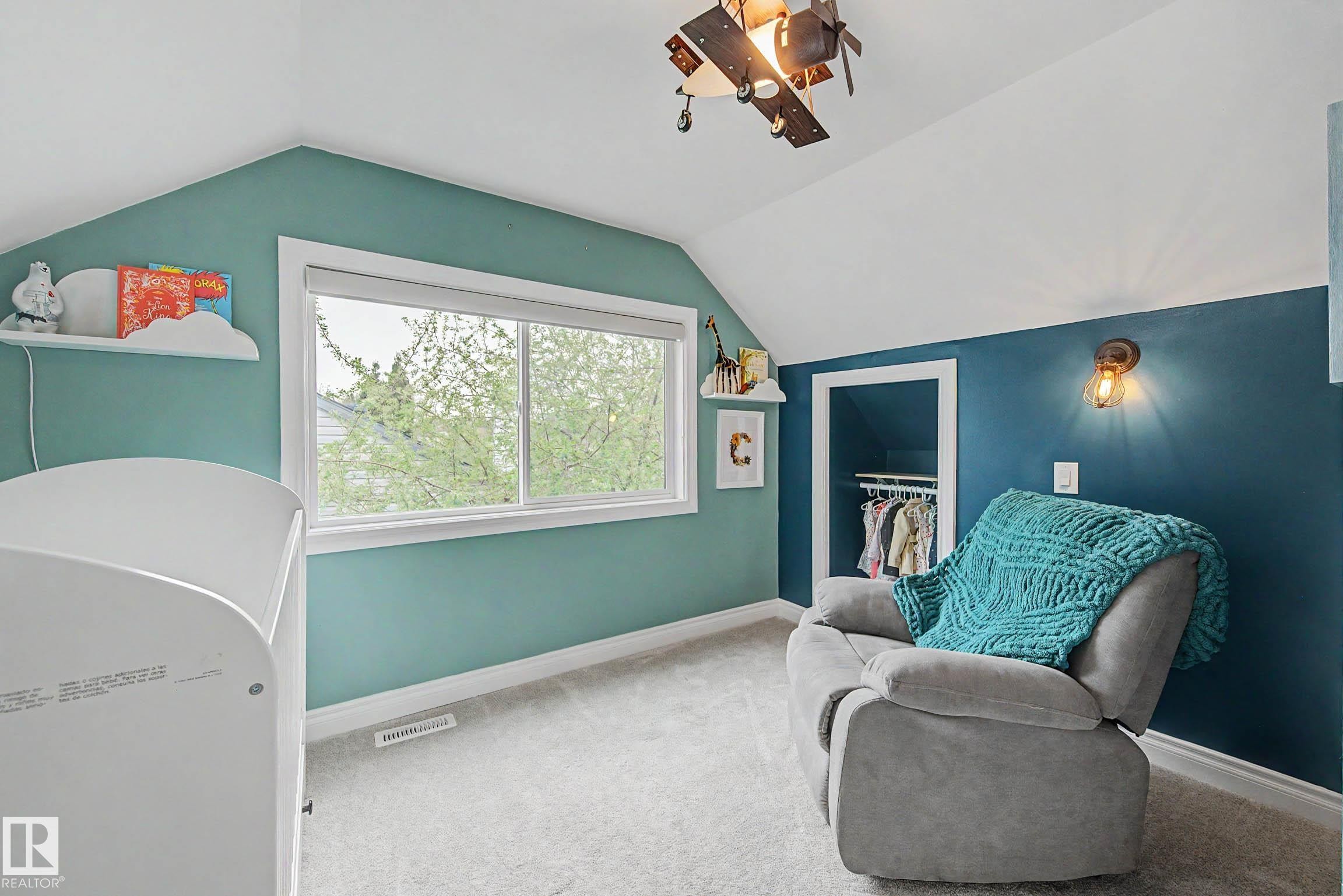 Bedroom featuring a large window, sloped ceilings, and mixed wall treatments - 13316 109A Avenue, Edmonton, AB - Indoor