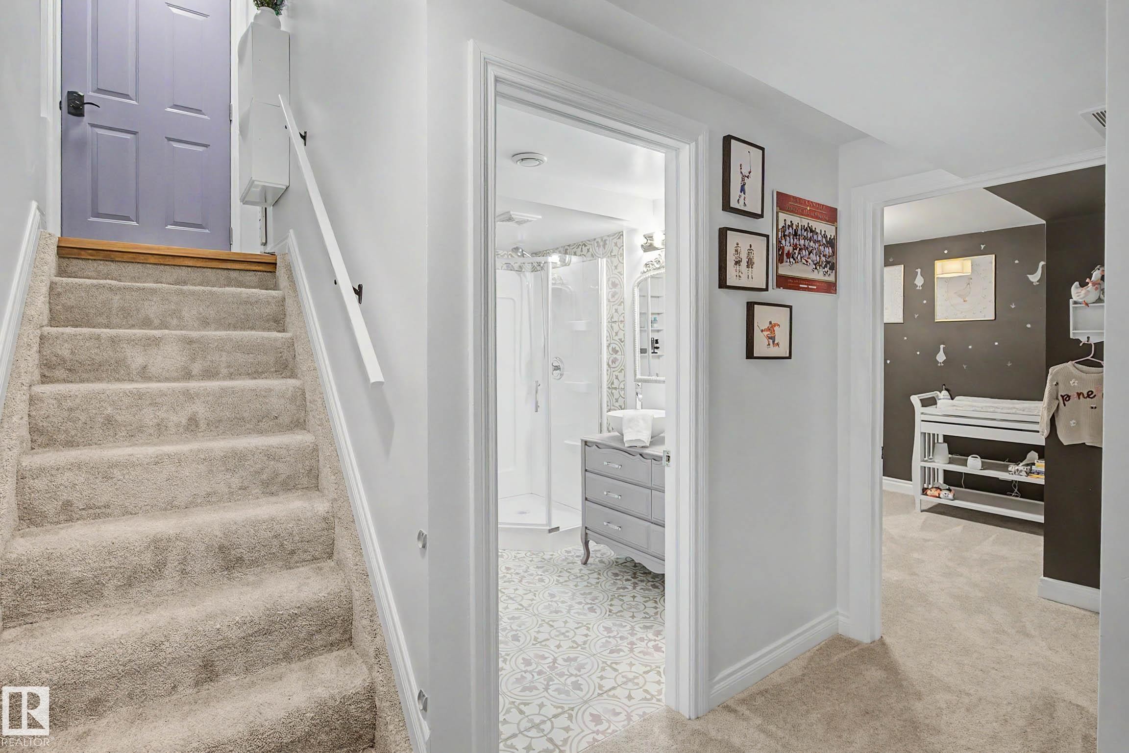 Carpeted staircase with a single handrail and a light purple paneled door at the top landing - 13316 109A Avenue, Edmonton, AB - Indoor Photo Showing Other Room
