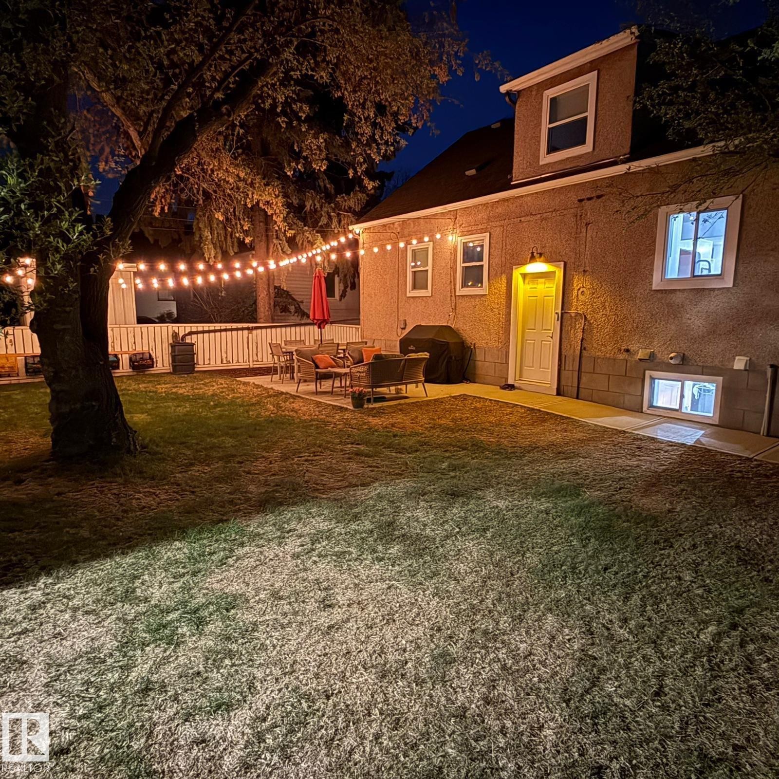 Manicured lawn with a spacious paver patio, featuring a white privacy fence and a mature tree - 13316 109A Avenue, Edmonton, AB - Outdoor