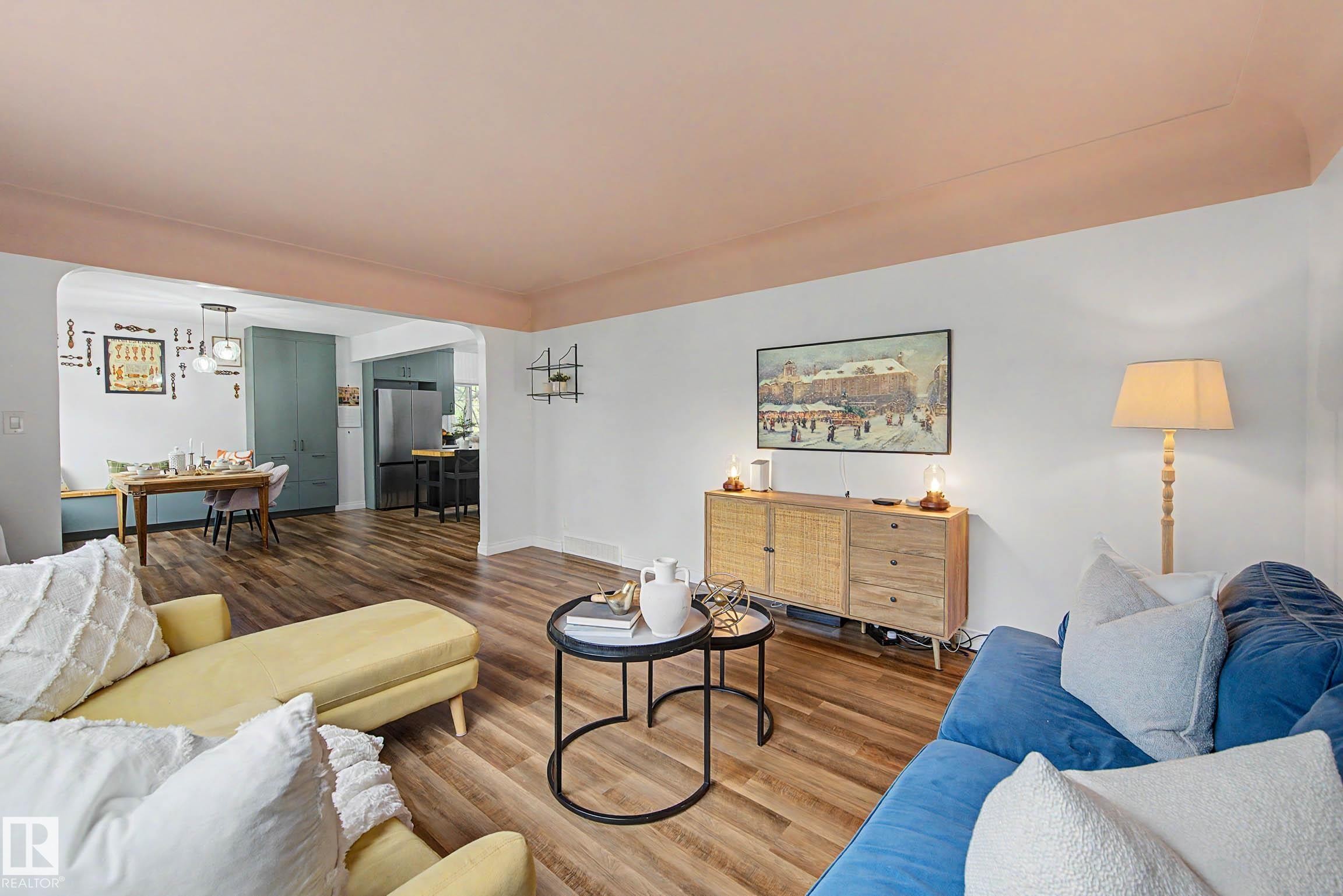Open-concept living space featuring wood-finish flooring, white walls, and a pink ceiling detail - 13316 109A Avenue, Edmonton, AB - Indoor Photo Showing Living Room