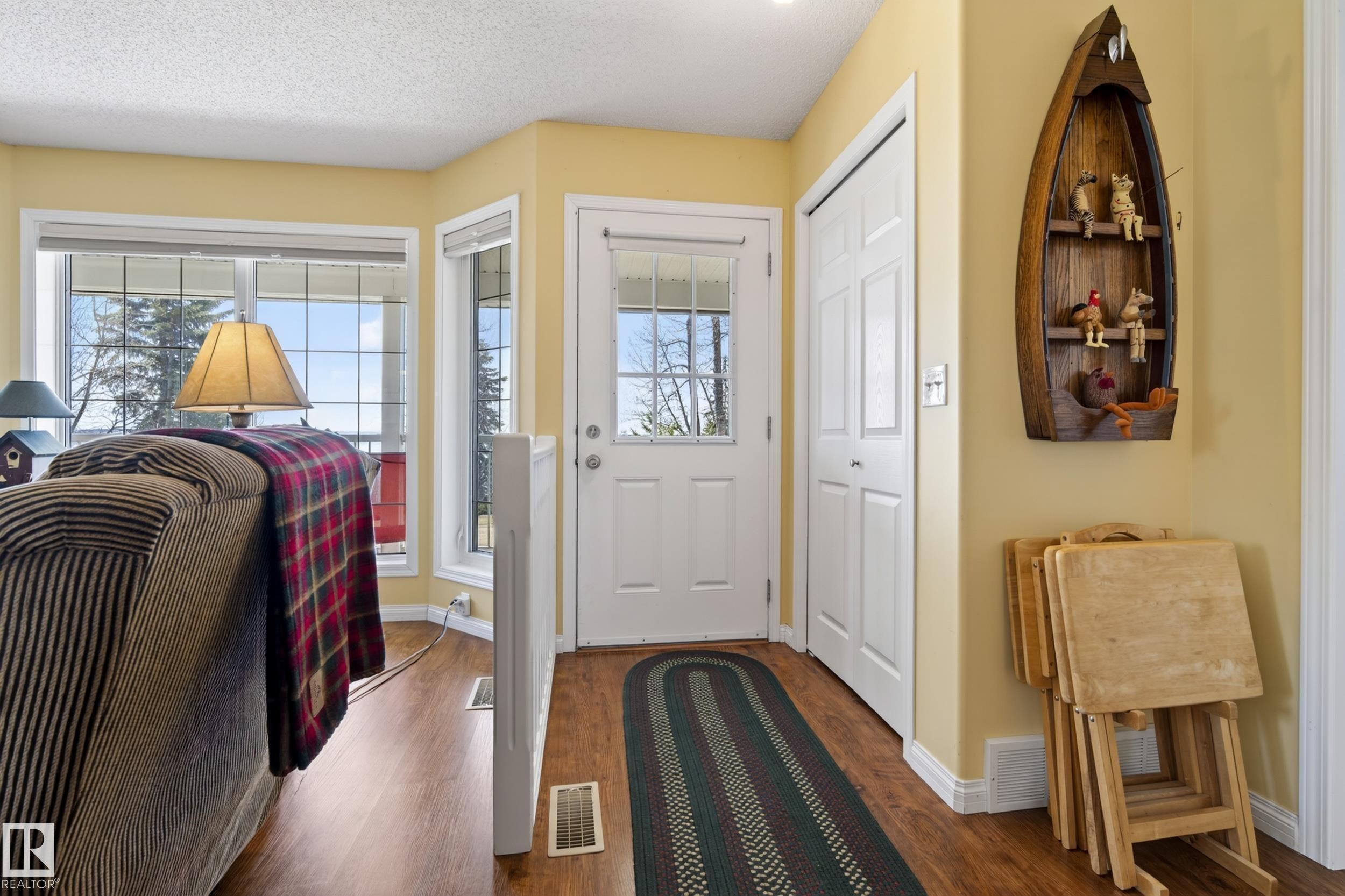Entrance area featuring wood-finish flooring, a white paneled door with window, and a built-in closet with bi-fold doors - 77 Lakeshore Drive, Rural Leduc County, AB - Indoor