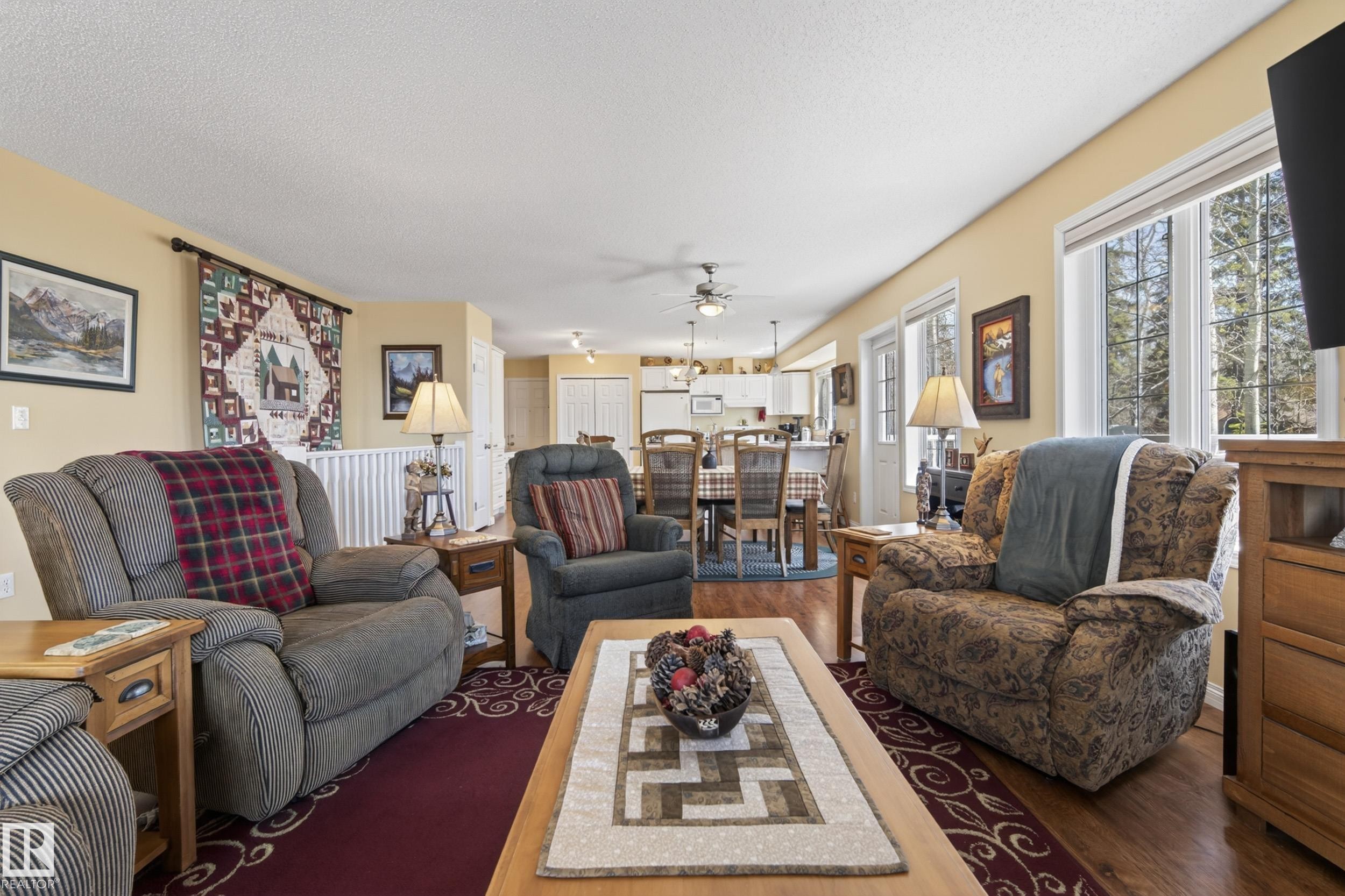 Spacious living area featuring wood-finish flooring, ample natural light from large windows, and a dedicated dining space - 77 Lakeshore Drive, Rural Leduc County, AB - Indoor Photo Showing Living Room