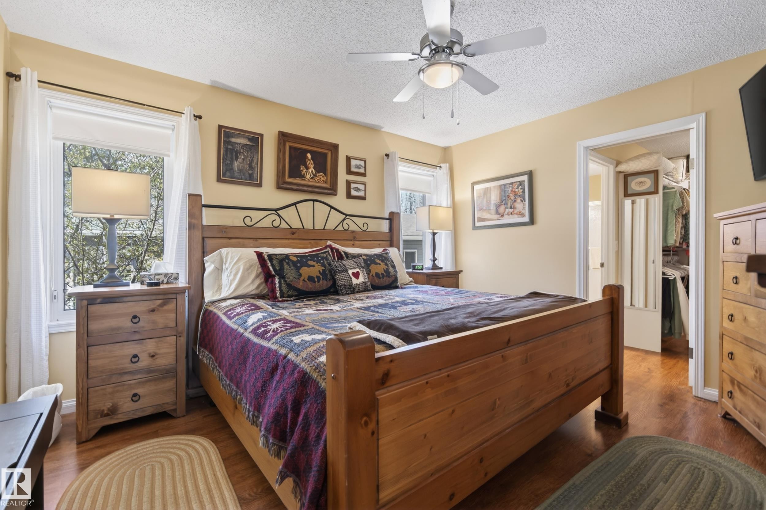 Bedroom featuring wood-finish flooring, two large windows, and a ceiling fan with integrated lighting - 77 Lakeshore Drive, Rural Leduc County, AB - Indoor Photo Showing Bedroom