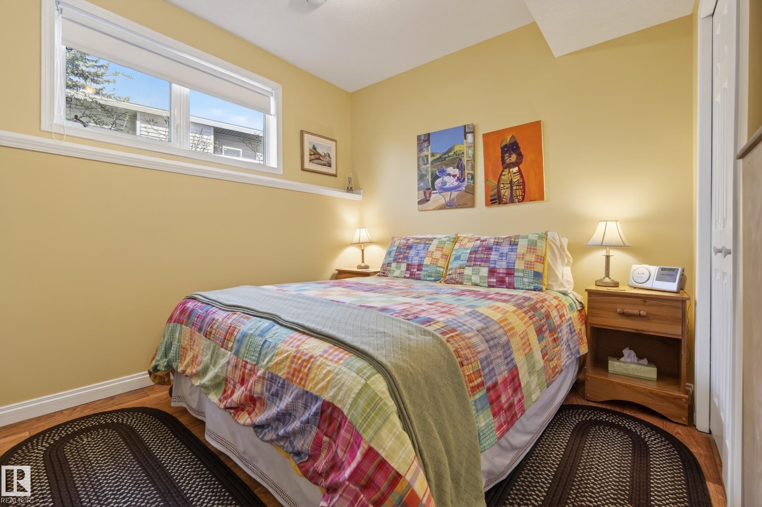 Bedroom featuring wood-finish flooring, a baseboard trim, and a window with a white frame - 77 Lakeshore Drive, Rural Leduc County, AB - Indoor Photo Showing Bedroom